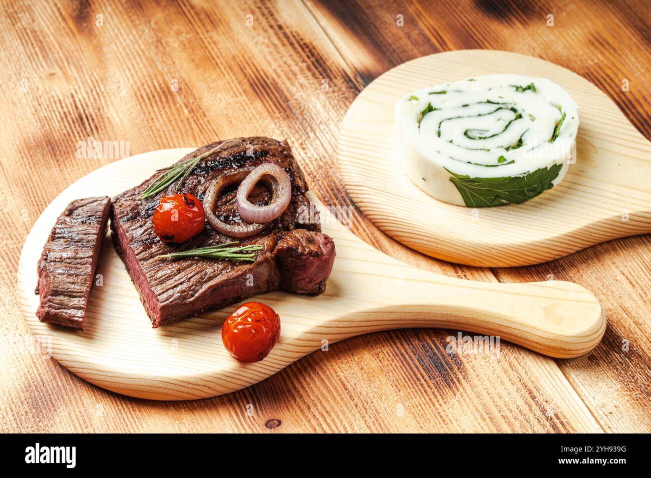 Steak de bœuf moyen-rare avec tomates cerises et fromage et rouleau d'herbes sur une planche de bois et fond. Photo de haute qualité Banque D'Images