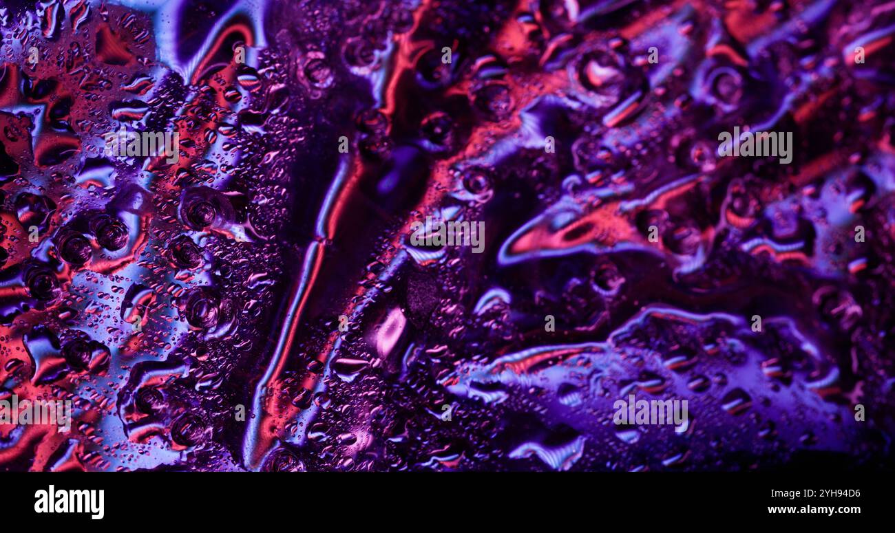 Humidité violette. ECLAIRAGE clignotant. Condensation liquide clignotante sur surface brillante humide avec éclaboussures spectrales scintillantes. Banque D'Images