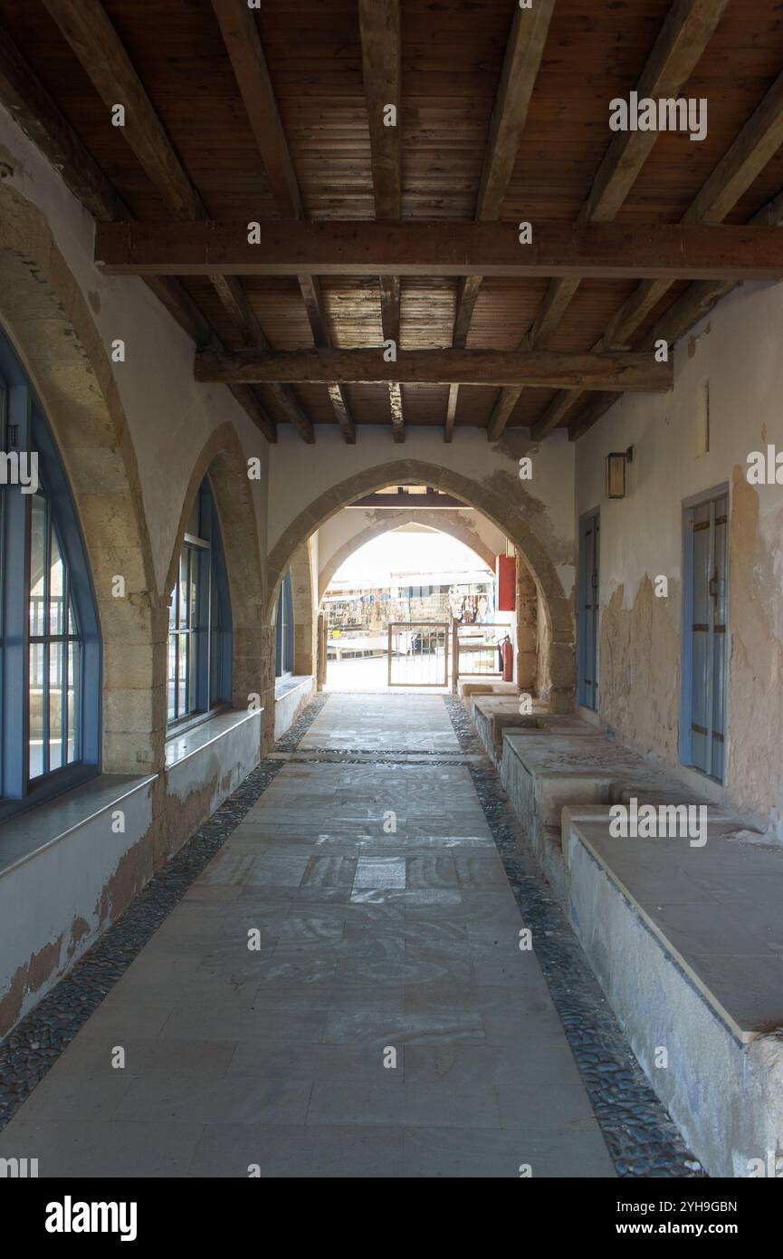 Un passage serein avec des arches s'ouvre sur une cour ensoleillée, évoquant un sentiment de paix et d'histoire. Banque D'Images