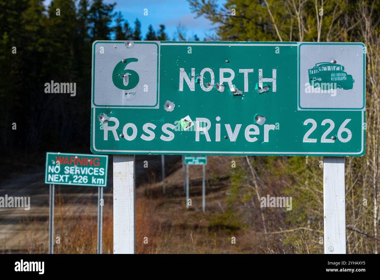 Panneau routier de Ross River dans le nord du Canada, territoire du Yukon vu pendant l'été avec des trous de balles dans les panneaux routiers. Banque D'Images