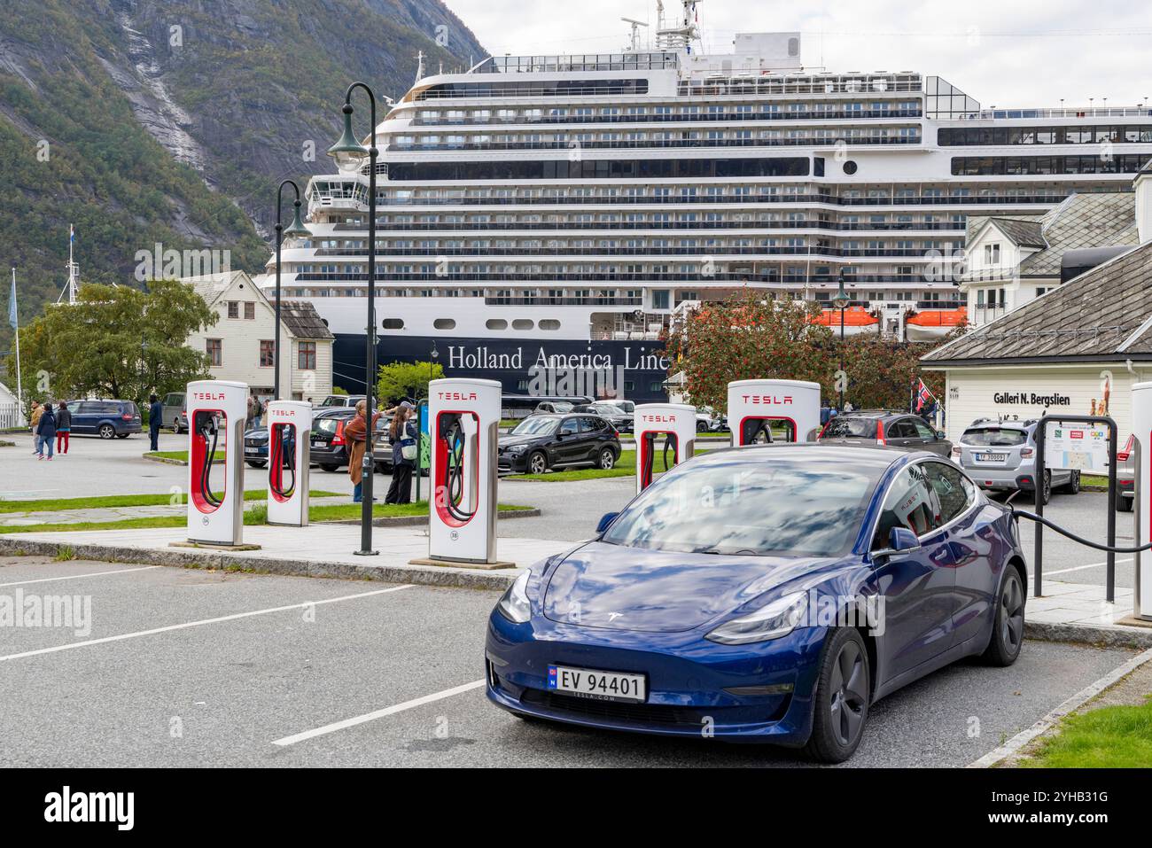 Tesla modèle 3 sur un compresseur Tesla public dans le village norvégien d'Eidfjord, avec la ligne Holland America MS Rotterdam en arrière-plan Banque D'Images