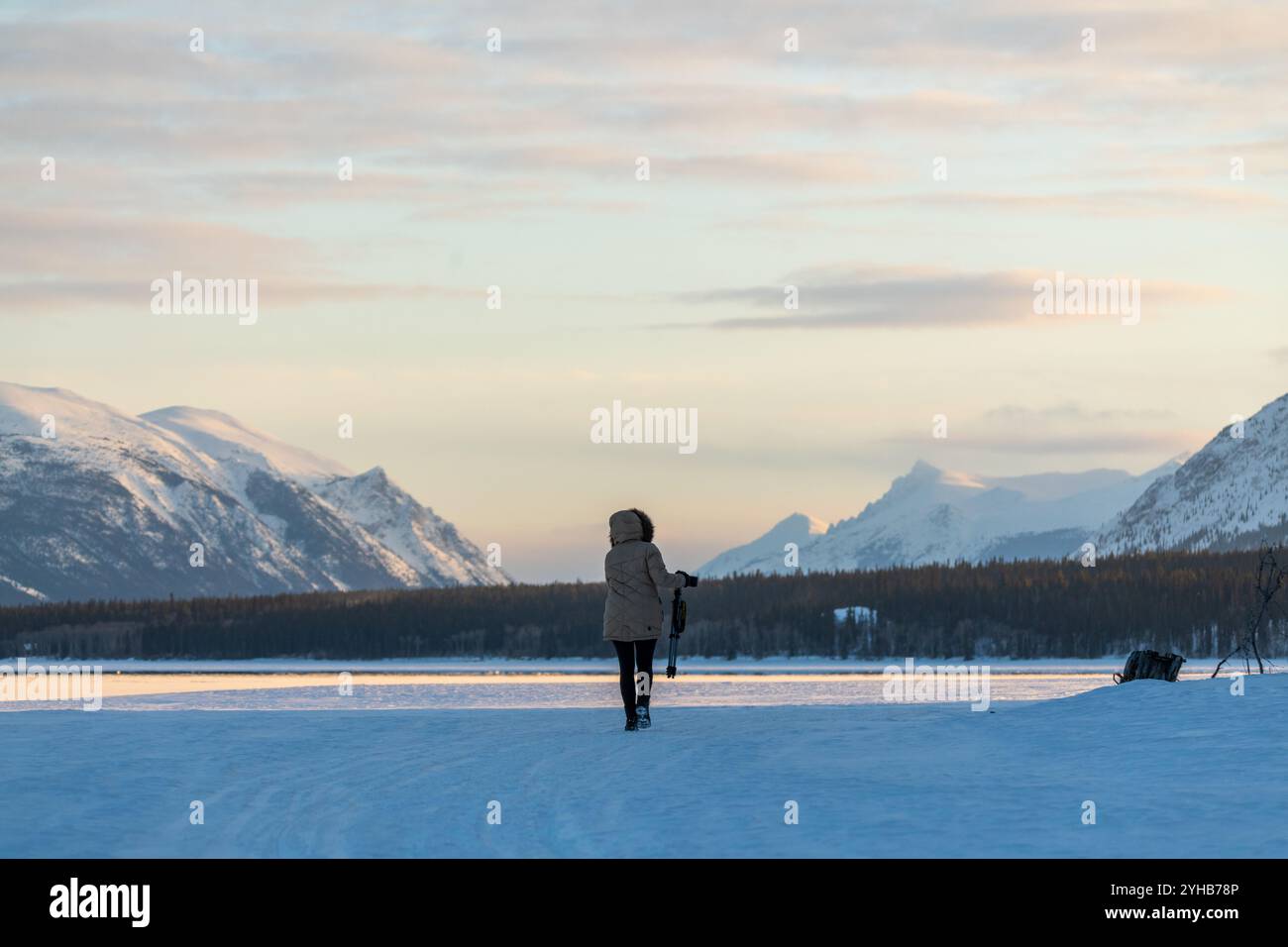 Énormes belles montagnes enneigées en arrière-plan avec femme en vêtements d'hiver complets debout au premier plan sur le lac gelé. Banque D'Images