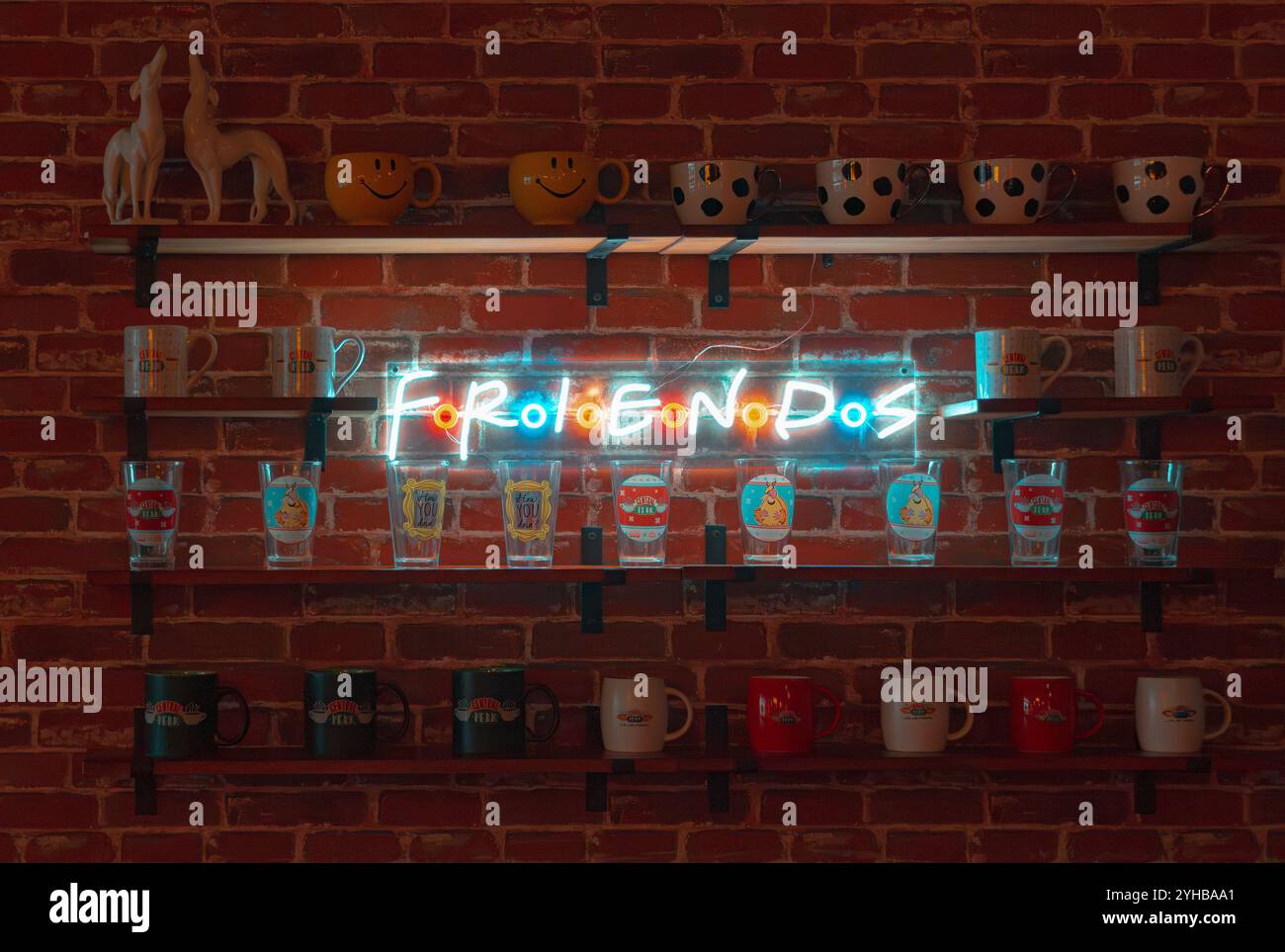 Un vif présentoir sur le thème des amis avec une enseigne au néon et des étagères remplies de tasses et de verres, capturant le charme nostalgique de cette émission de télévision emblématique Banque D'Images