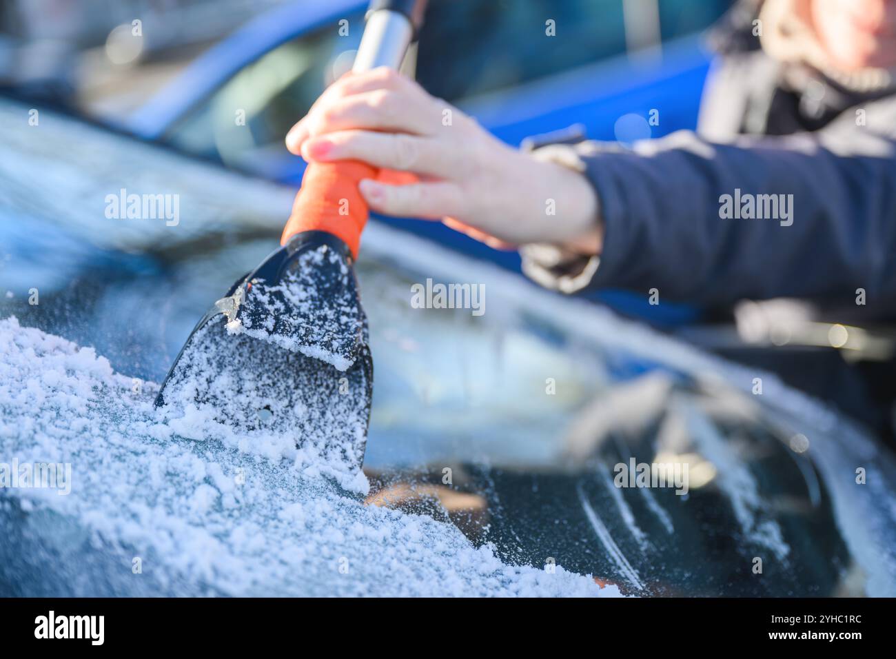 Femme dégivrant pare-brise de voiture avec grattoir à glace, mise au point sélective Banque D'Images