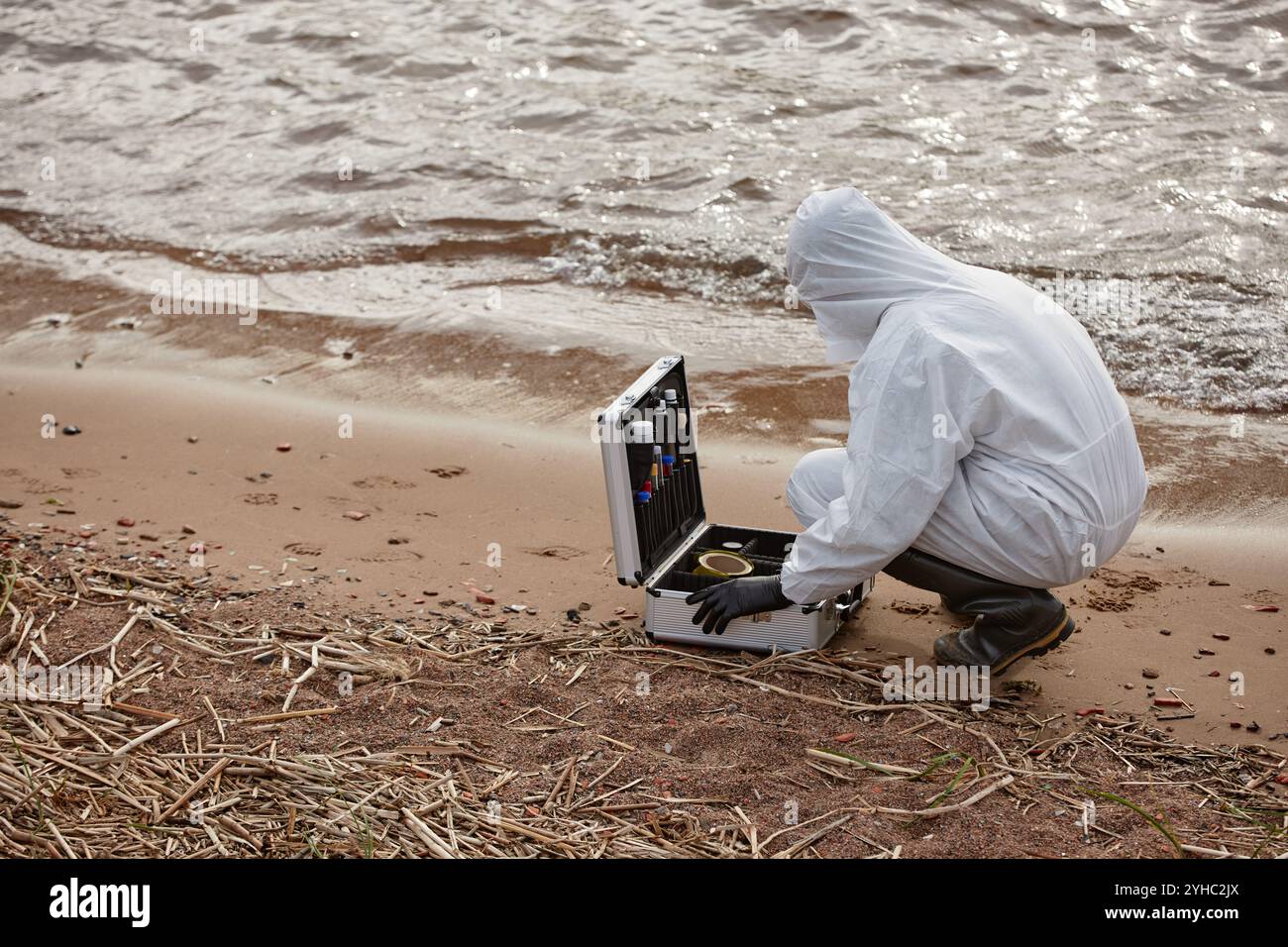 Vue latérale d'un scientifique méconnaissable portant une combinaison de protection et un kit de test d'ouverture tout en faisant des sondes sur l'eau à l'extérieur, copier l'espace Banque D'Images