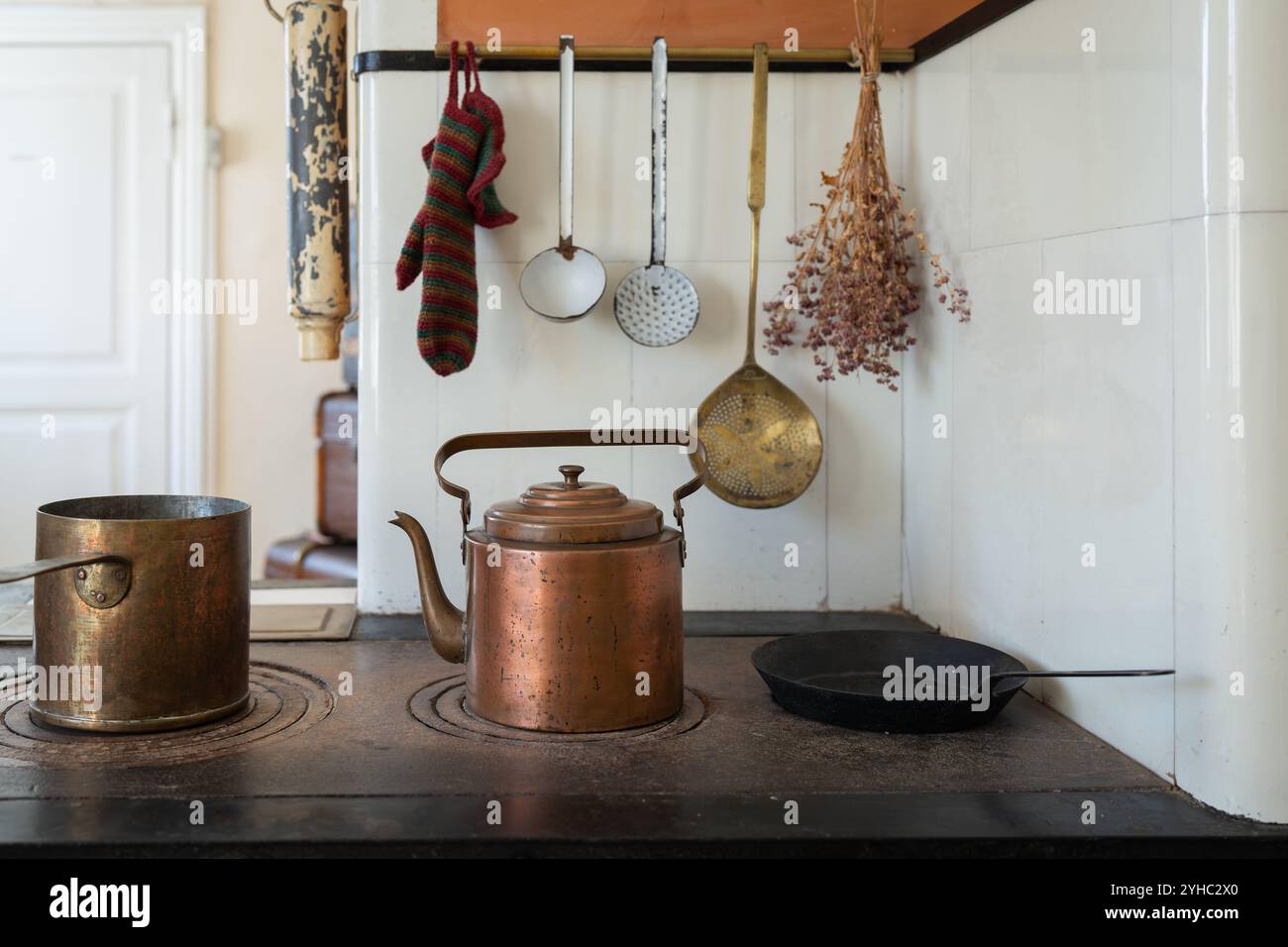 Un intérieur de cuisine à l'ancienne. Pot de cuivre et bouilloire sur le poêle de cuisson au feu de bois. Ensemble d'anciens ustensiles de cuisine. Banque D'Images