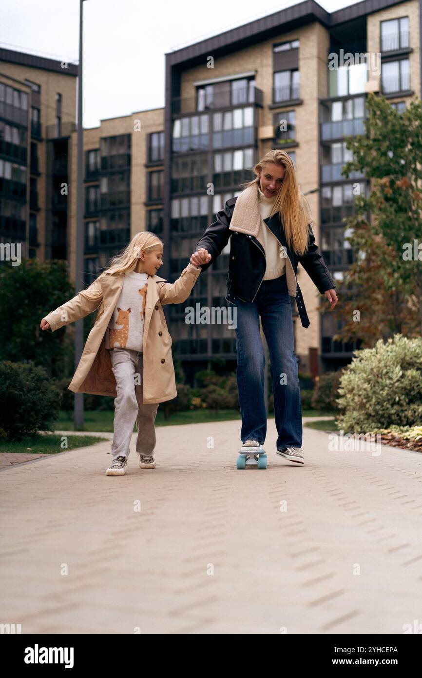Maman et fille skateboard dans un parc de la ville Banque D'Images