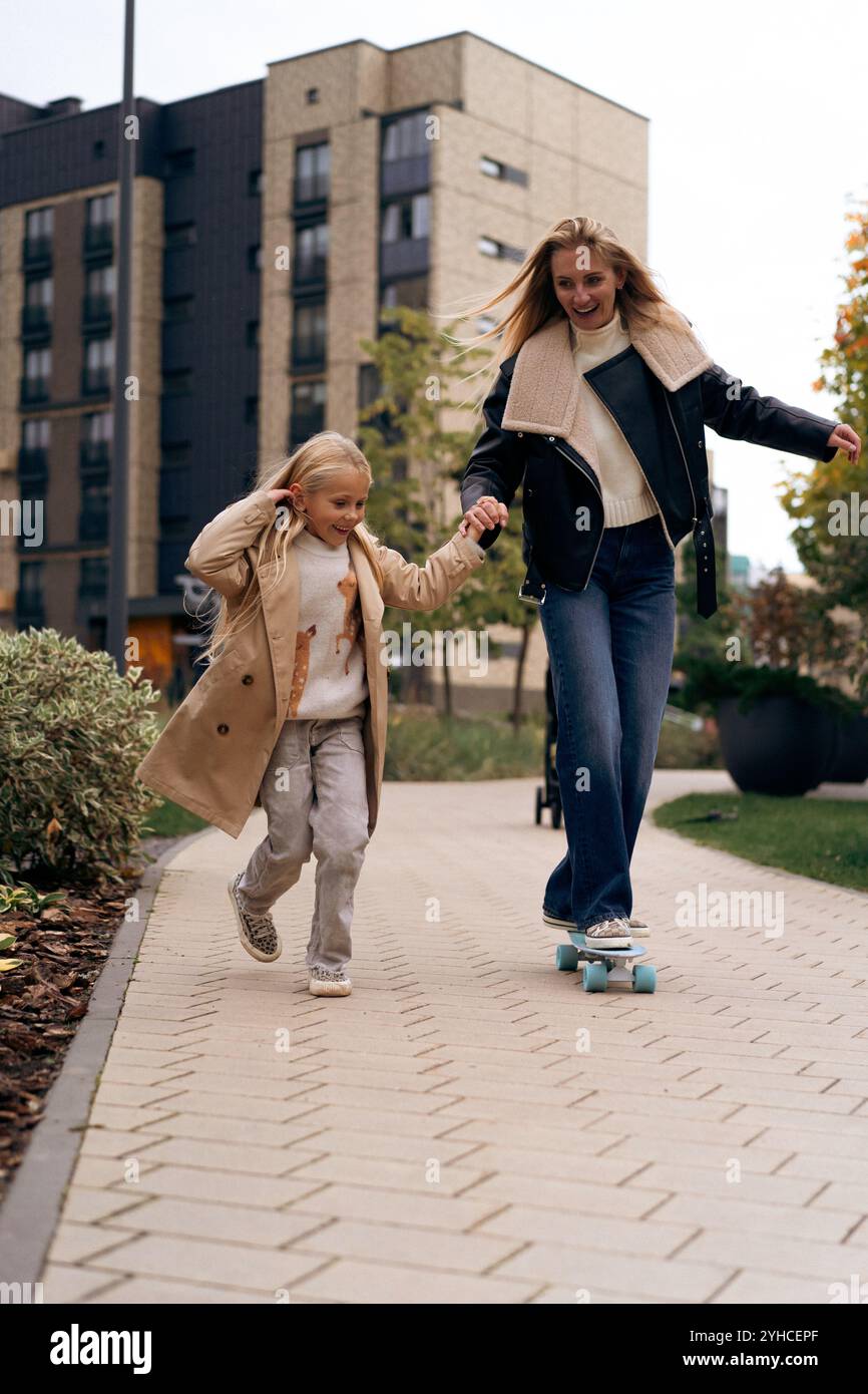 Maman et fille skateboard dans un parc de la ville Banque D'Images