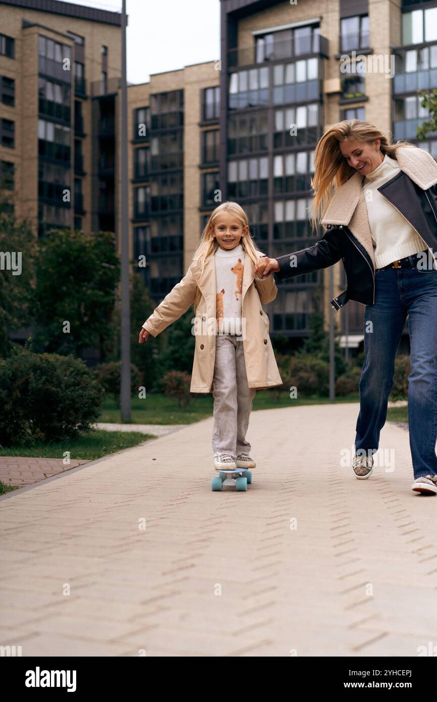 Maman et fille skateboard dans un parc de la ville Banque D'Images