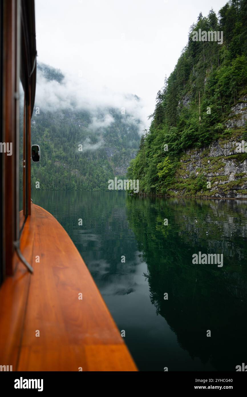 Promenade sereine en bateau sur Königssee dans le parc national de Berchtesgaden, Allemagne. Les falaises couvertes de brume se reflètent dans l'eau calme. Banque D'Images