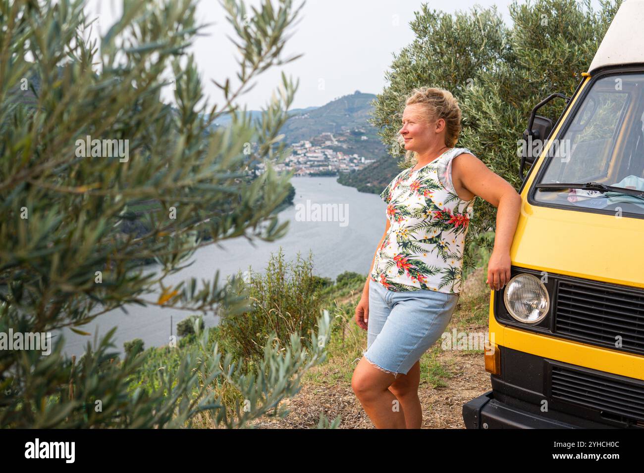 Femme blonde profitant de la vue debout près de son camping-car rétro dans la vallée du Douro, Portugal Banque D'Images