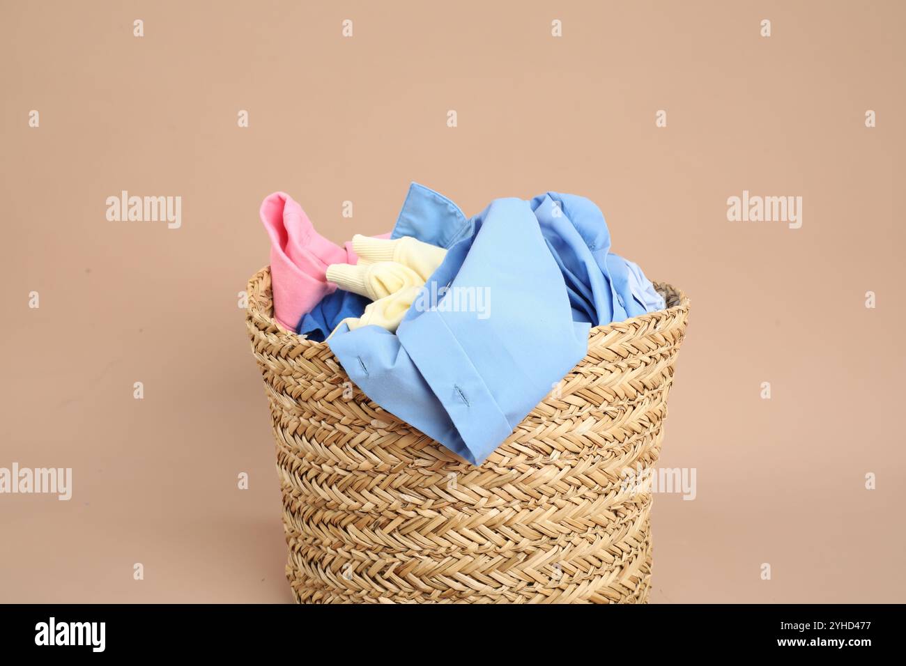 Panier en osier plein de linge sur fond beige Banque D'Images