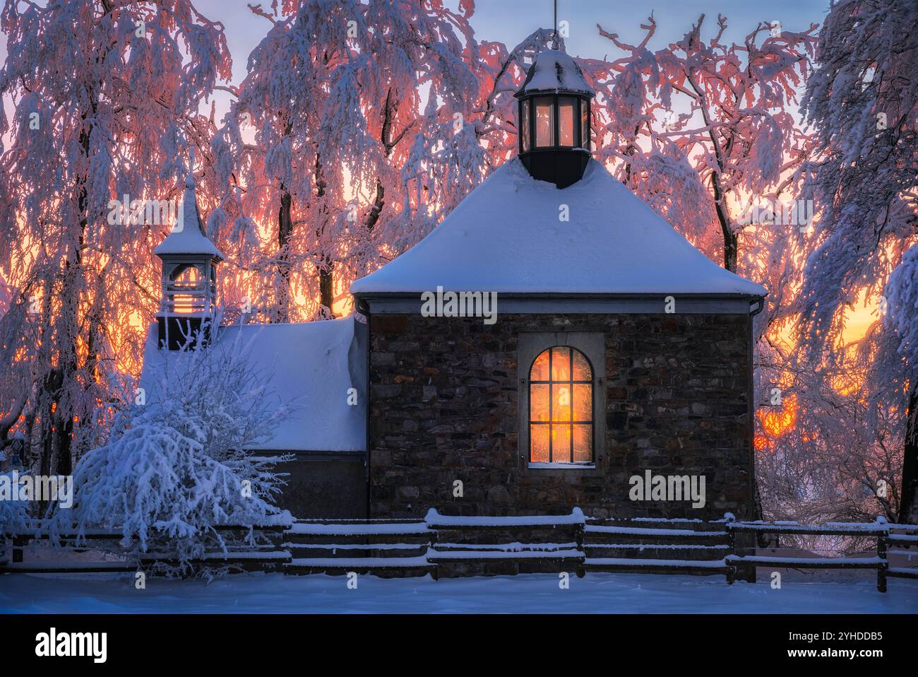 Chapelle enneigée au coucher du soleil avec une lumière chaude dans la forêt d'hiver dans les Hautes Fagnes de Belgique Banque D'Images
