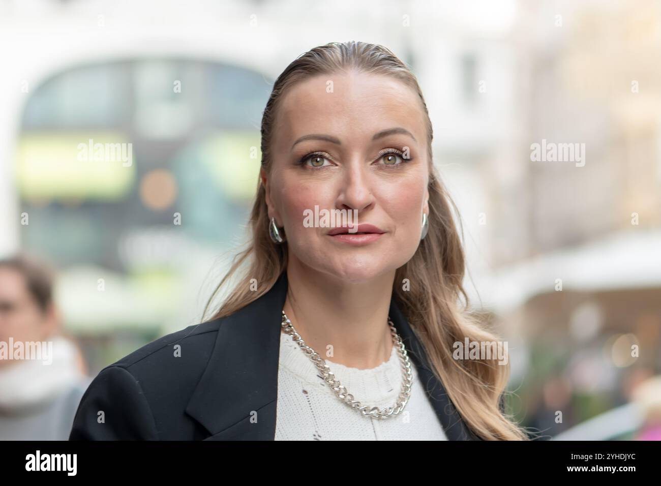 Portrait d'une femme sophistiquée d'apparence européenne, 35-40 ans, avec un flou d'une ville moderne en arrière-plan. Banque D'Images