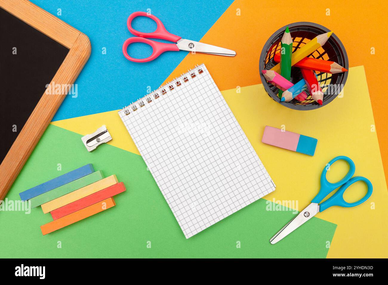 Matériaux de dessin et d'artisanat. Ensemble créativité pour enfant. Ciseaux, craie, tableau noir, crayons de couleur, taille-crayons, gomme à effacer en arrière-plan. Papier coloré. Banque D'Images