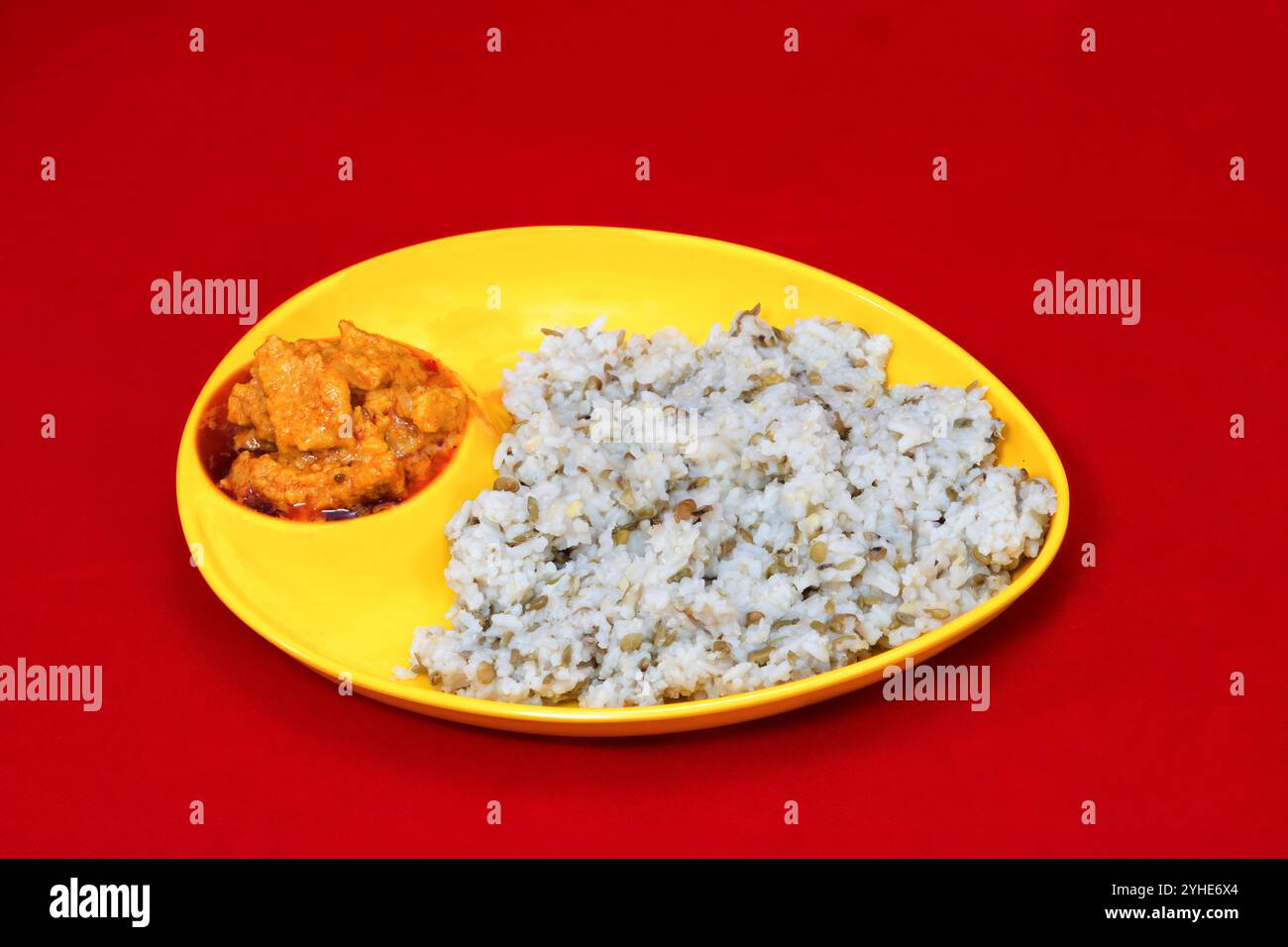 Vue rapprochée du Gujarati Kathiyawadi Dhokali Sabji épicé avec khichdi, sur un plat jaune bien en évidence, placé sur un fond rouge Banque D'Images