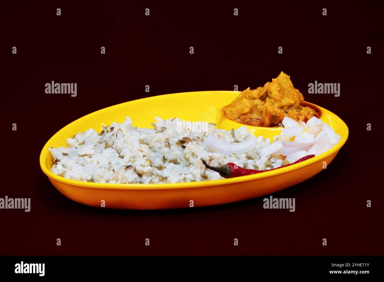 Vue latérale droite du Gujarati Kathiyawadi Dhokali Sabji épicé avec khichdi, sur plat jaune bien en évidence, placé sur un fond noir Banque D'Images