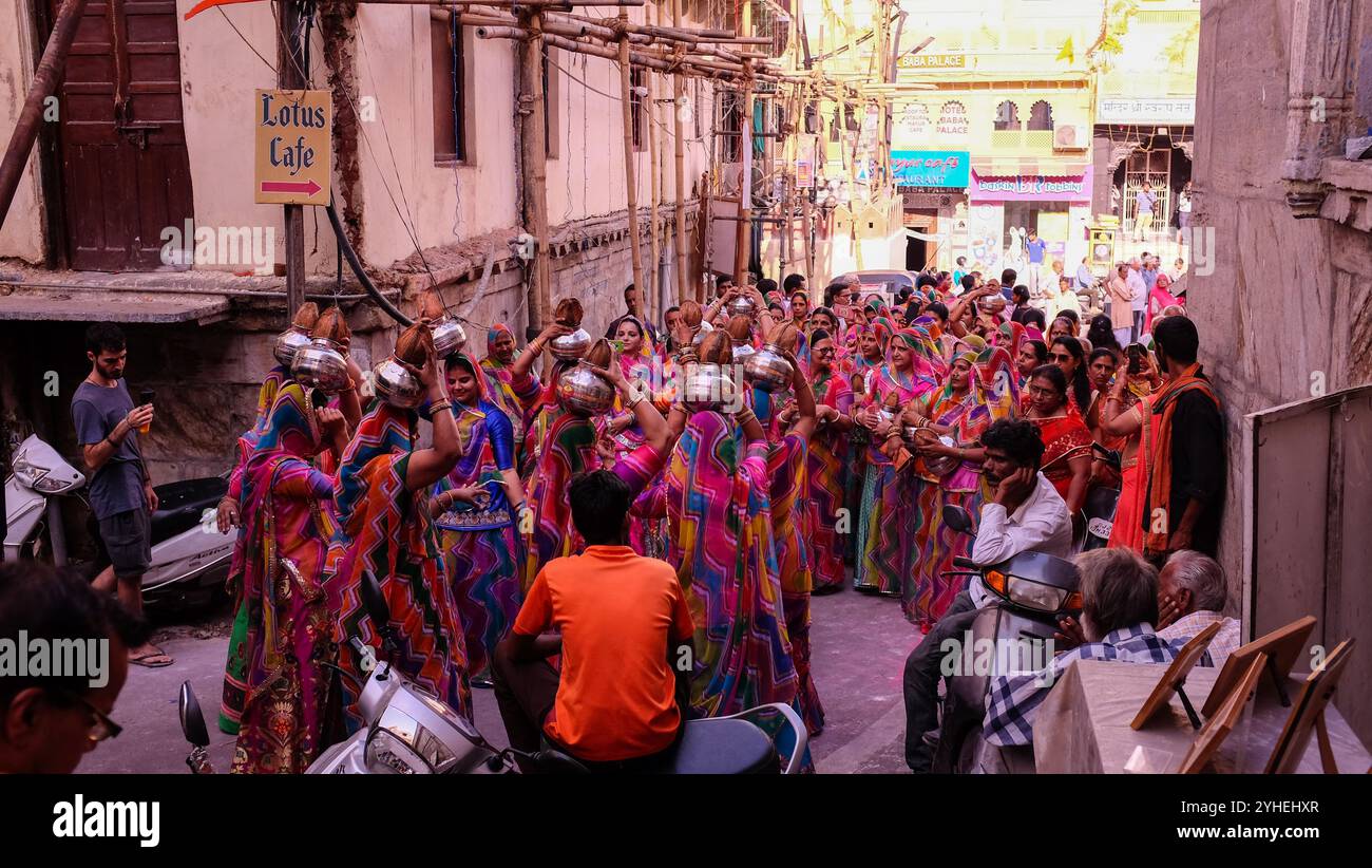 La fête nuptiale lors d'un mariage danse dans les rues d'Udaipur comme les habitants et les touristes observent Banque D'Images