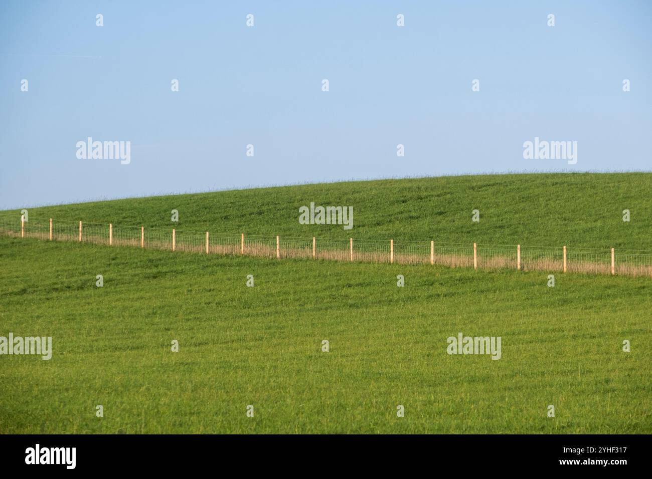 Une ligne de poteaux de clôture traversant un champ verdoyant au sommet d'une colline un jour d'automne ensoleillé, Worcestershire, Angleterre. Banque D'Images