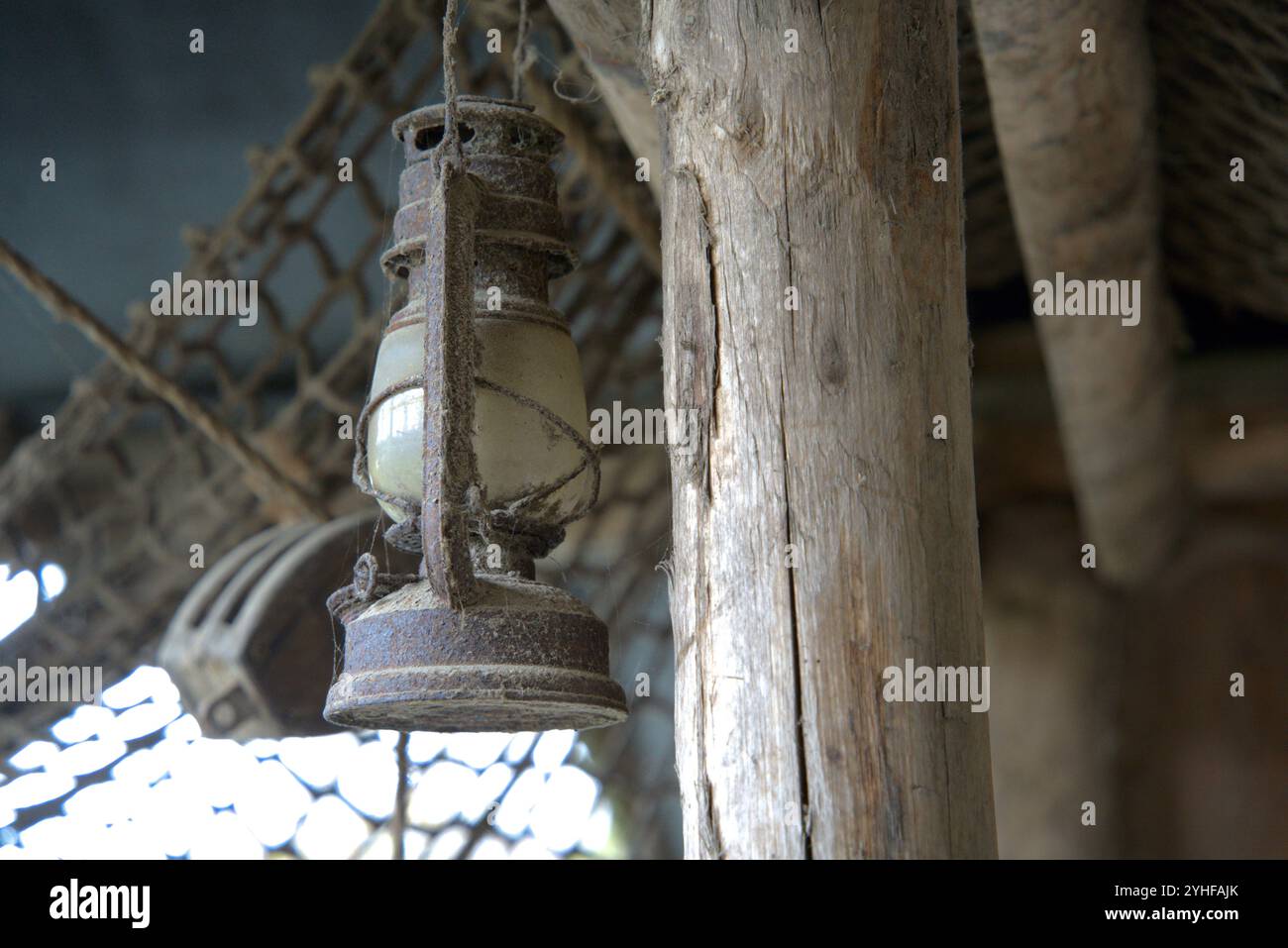 Weathered Glow : lanterne rouillée poussiéreuse suspendue dans une cabane en bois Banque D'Images