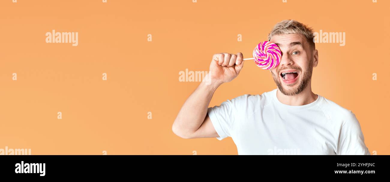 L'homme heureux ferme l'œil avec la lollipop arc-en-ciel Banque D'Images