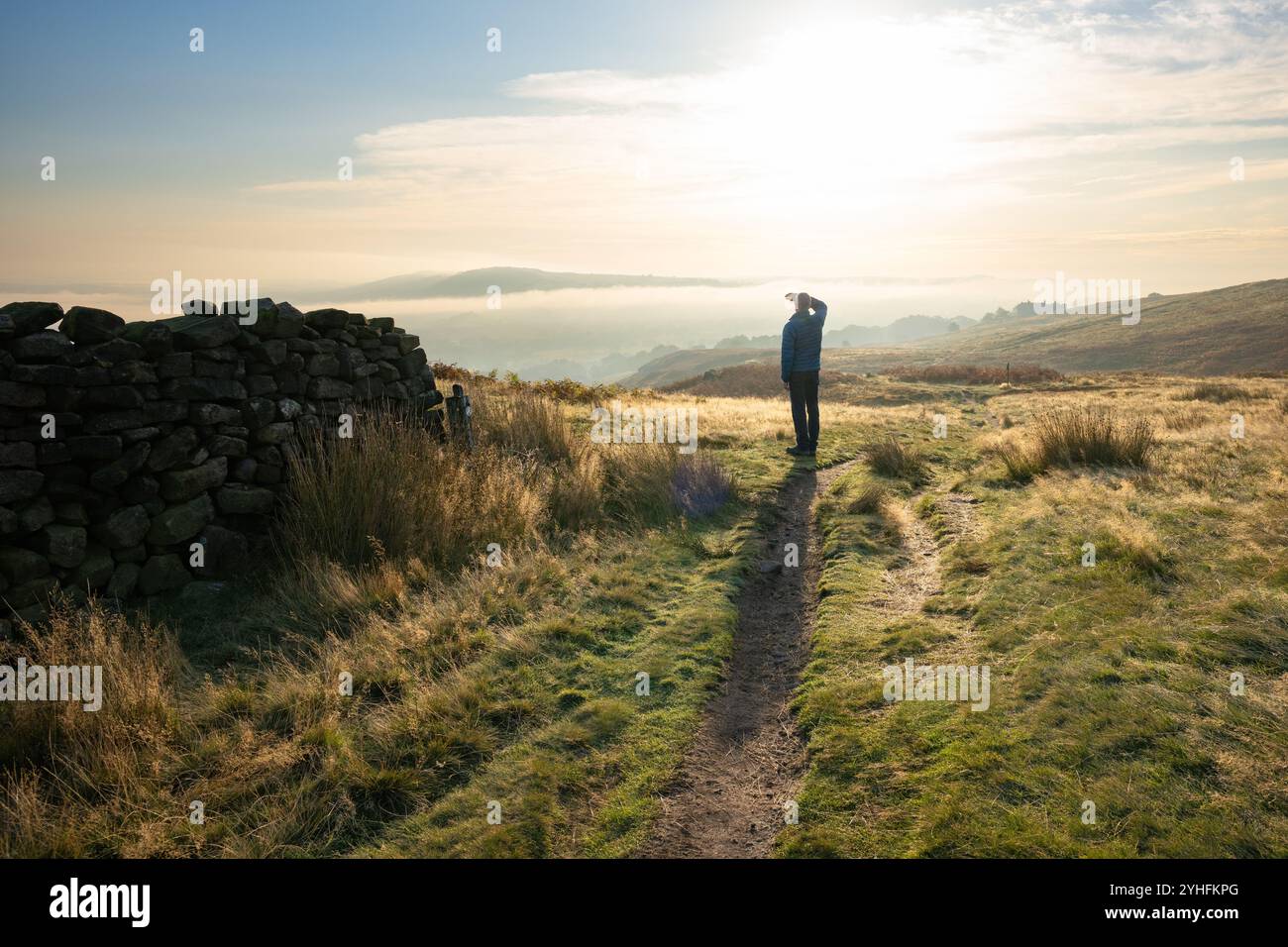 Burley Moor, Burley in Wharfedale, Ilkley, West Yorkshire, Angleterre, Royaume-Uni - homme regardant vers le bas sur Burley à Wharfedale enveloppé dans la brume tôt le matin Banque D'Images
