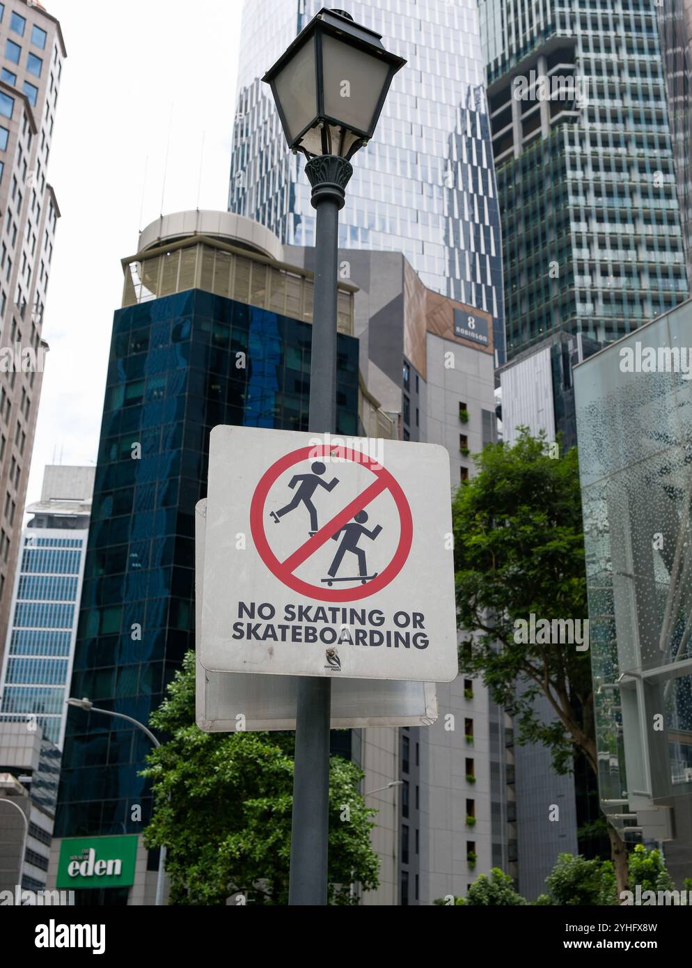 Aucun panneau d'avertissement de patinage ou de skateboard accroché à un lampadaire dans le quartier financier de la ville de Singapour parmi les gratte-ciel. Banque D'Images