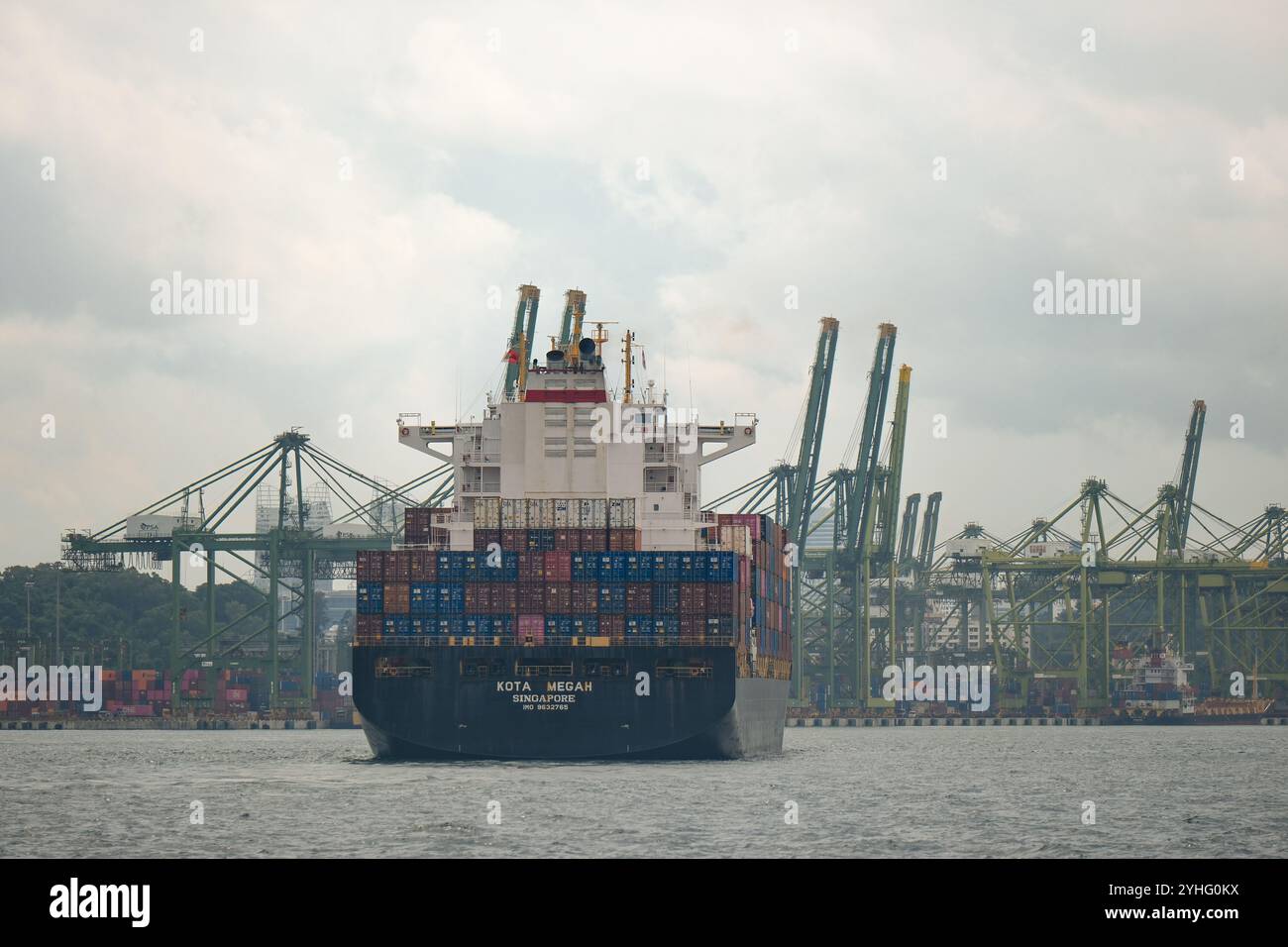 Le porte-conteneurs KOTA MEGAH navigue dans le port de Singapour avec l'horizon de Singapour en arrière-plan. Banque D'Images