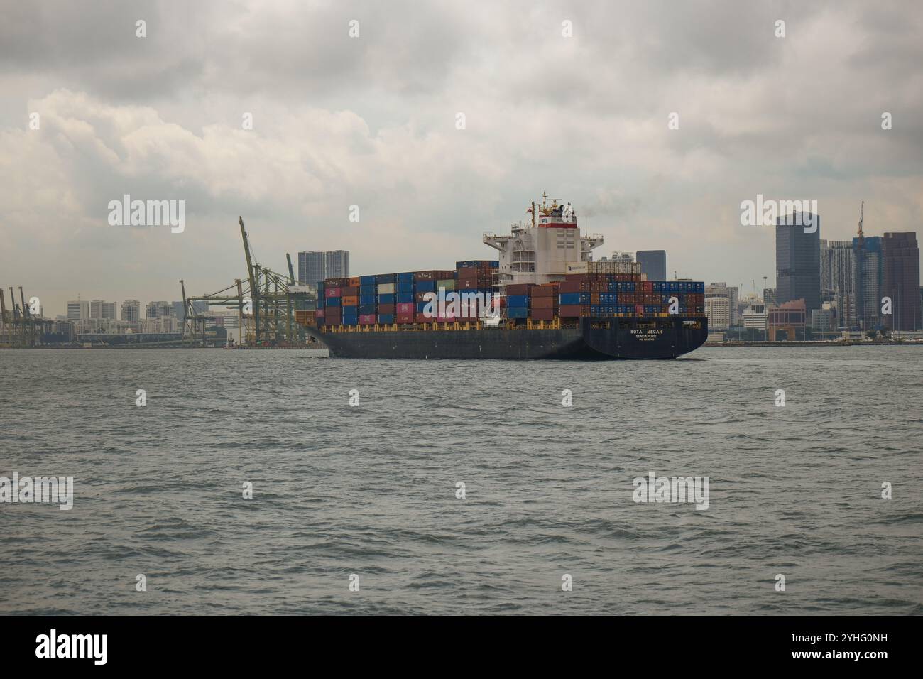 Le porte-conteneurs KOTA MEGAH navigue dans le port de Singapour avec l'horizon de Singapour en arrière-plan. Banque D'Images