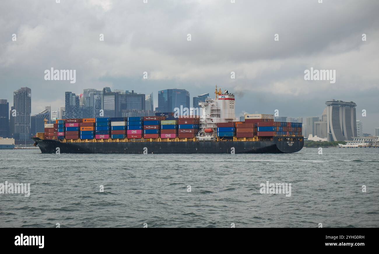 Le porte-conteneurs KOTA MEGAH navigue dans le port de Singapour avec l'horizon de Singapour en arrière-plan. Banque D'Images