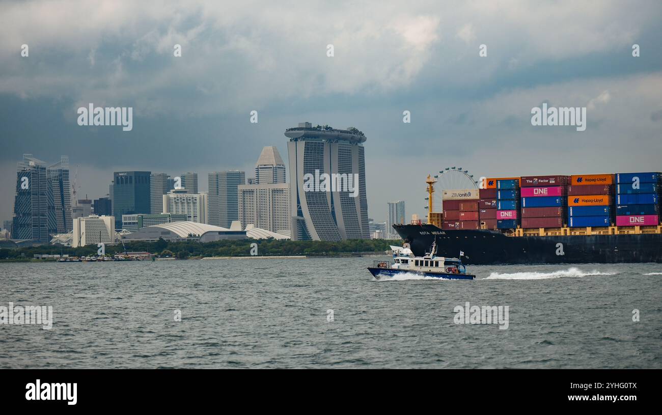 Le porte-conteneurs KOTA MEGAH navigue dans le port de Singapour avec l'horizon de Singapour en arrière-plan. Banque D'Images