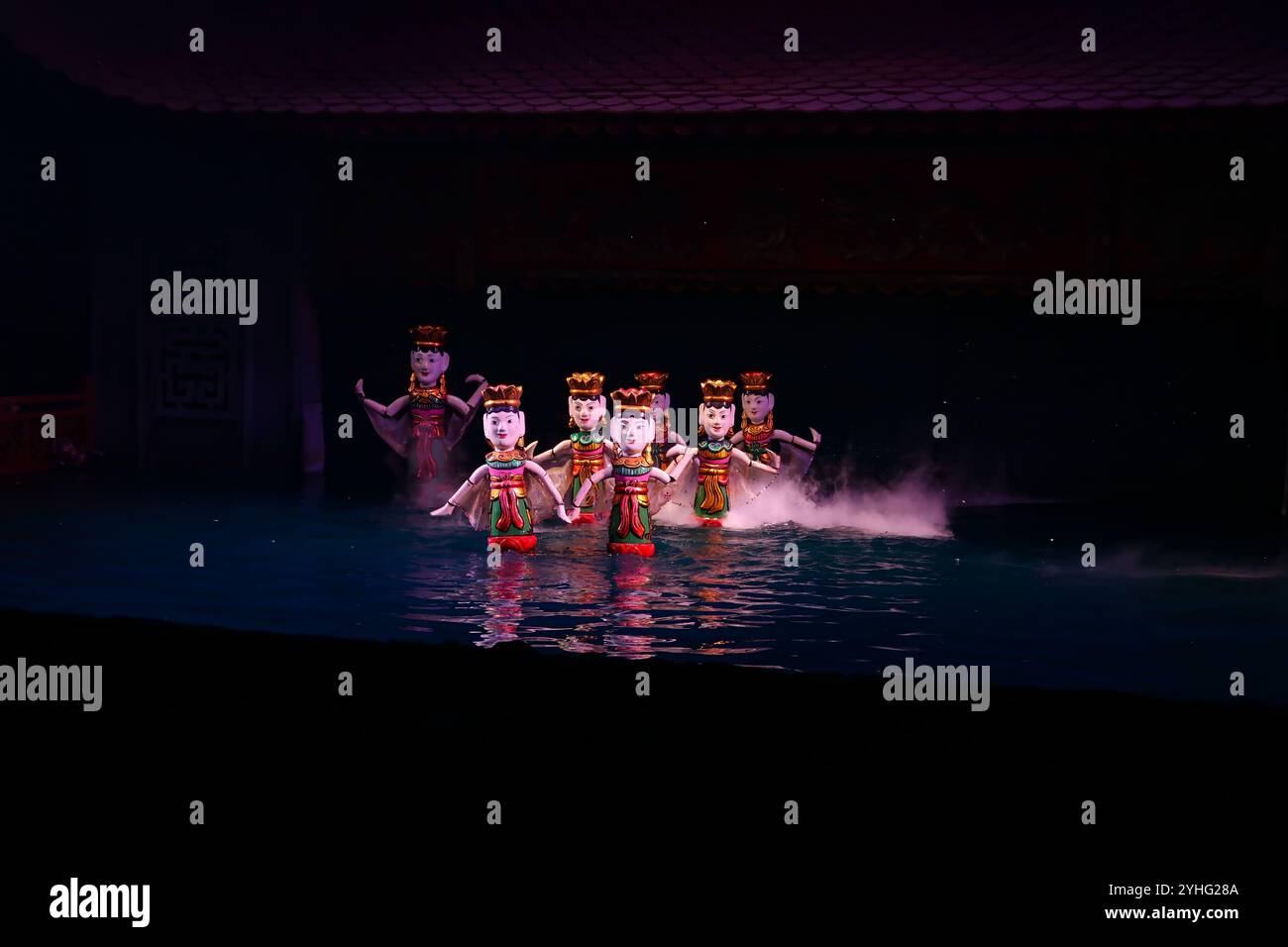 Une scène captivante d'un spectacle vietnamien de marionnettes sur l'eau, mettant en vedette des marionnettes traditionnelles vêtues de costumes vibrants, dansant gracieusement sur l'eau. Banque D'Images