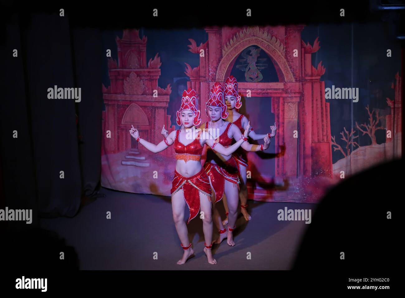 Trois danseurs en costumes rouges complexes se produisent à l'unisson, mettant en valeur la danse vietnamienne traditionnelle sur le thème du temple à Hoi an. Banque D'Images