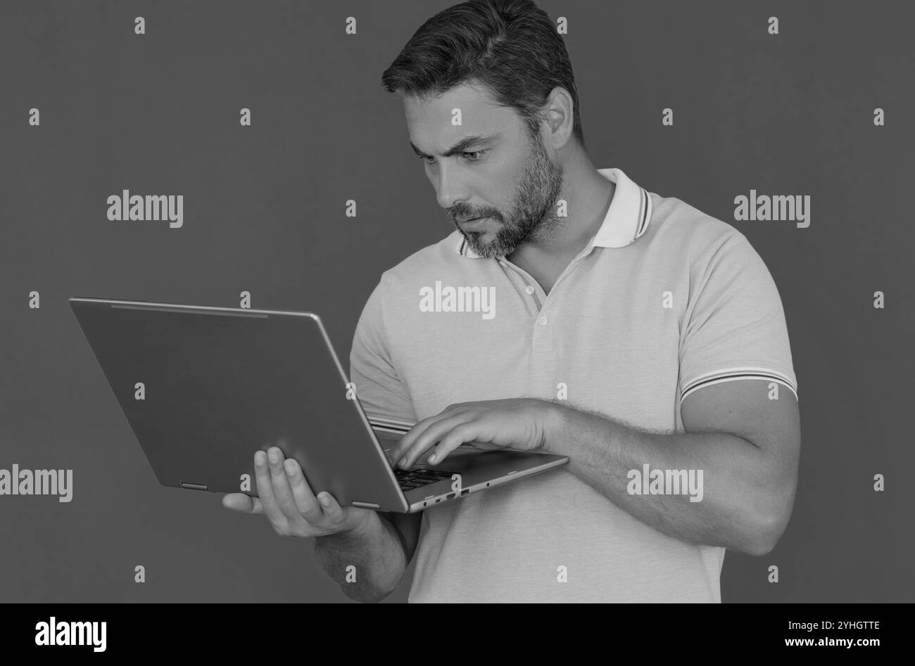 Homme millénaire travaillant sur ordinateur portable en studio. Homme hispanique vérifiant des informations sur un ordinateur portable, tapant des informations sur un ordinateur portable. Homme d'âge moyen cherchant Banque D'Images