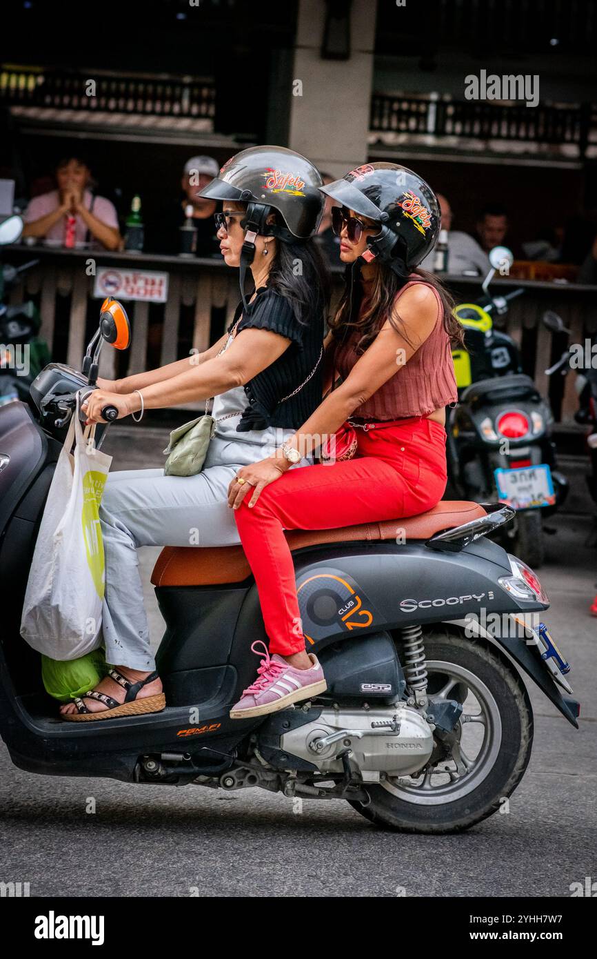 Deux filles thaïlandaises assises sur une moto ou un scooter font leur chemin le long de soi Buakhao, Pattaya City, Thaïlande. Banque D'Images