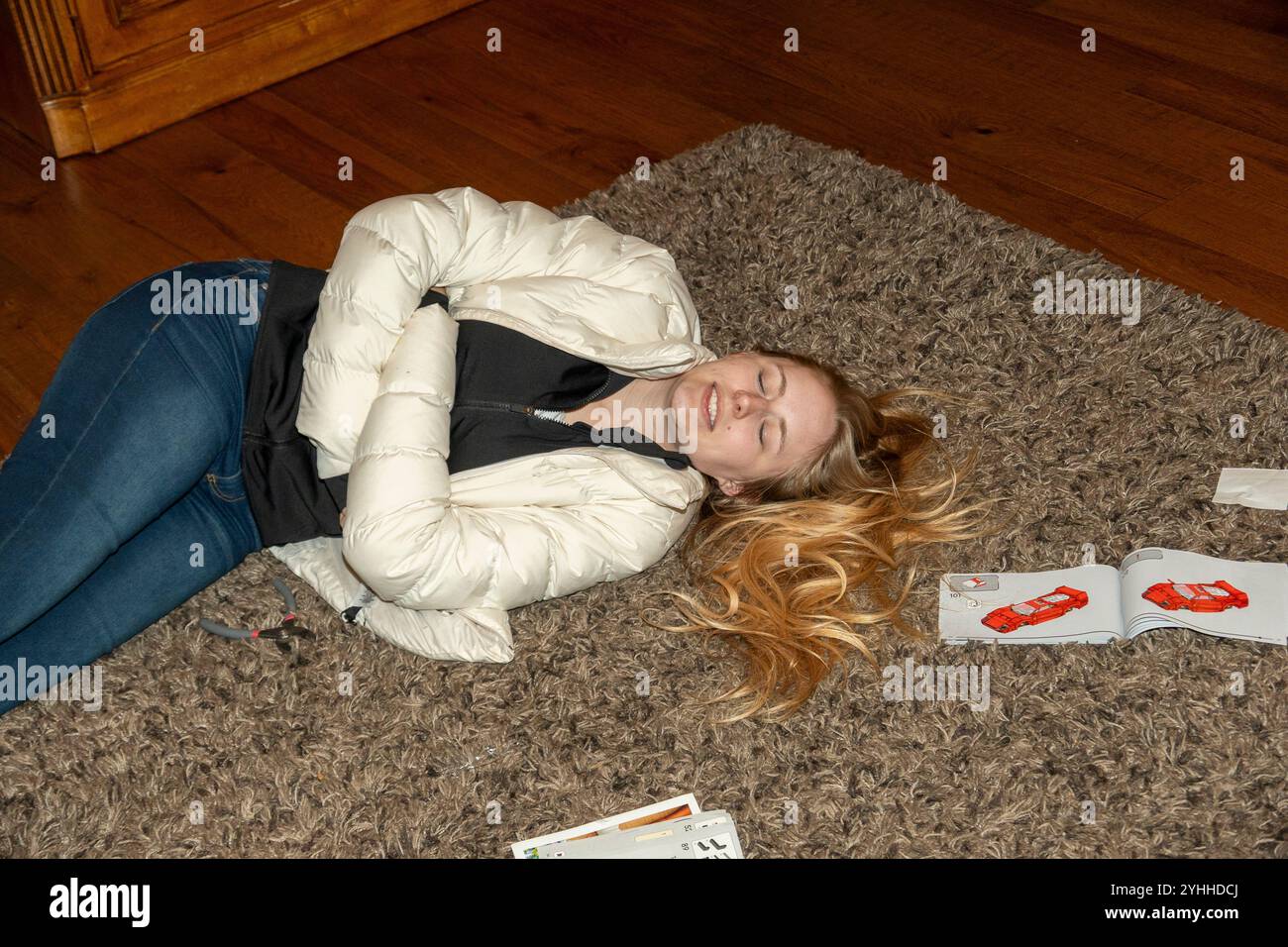 Femme se relaxant sur un sol recouvert de moquette entourée de magazines colorés dans un cadre intérieur confortable Banque D'Images