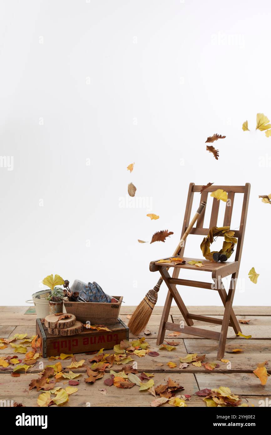 Chaise en bois, balai et feuilles mortes volantes sur le pont Banque D'Images