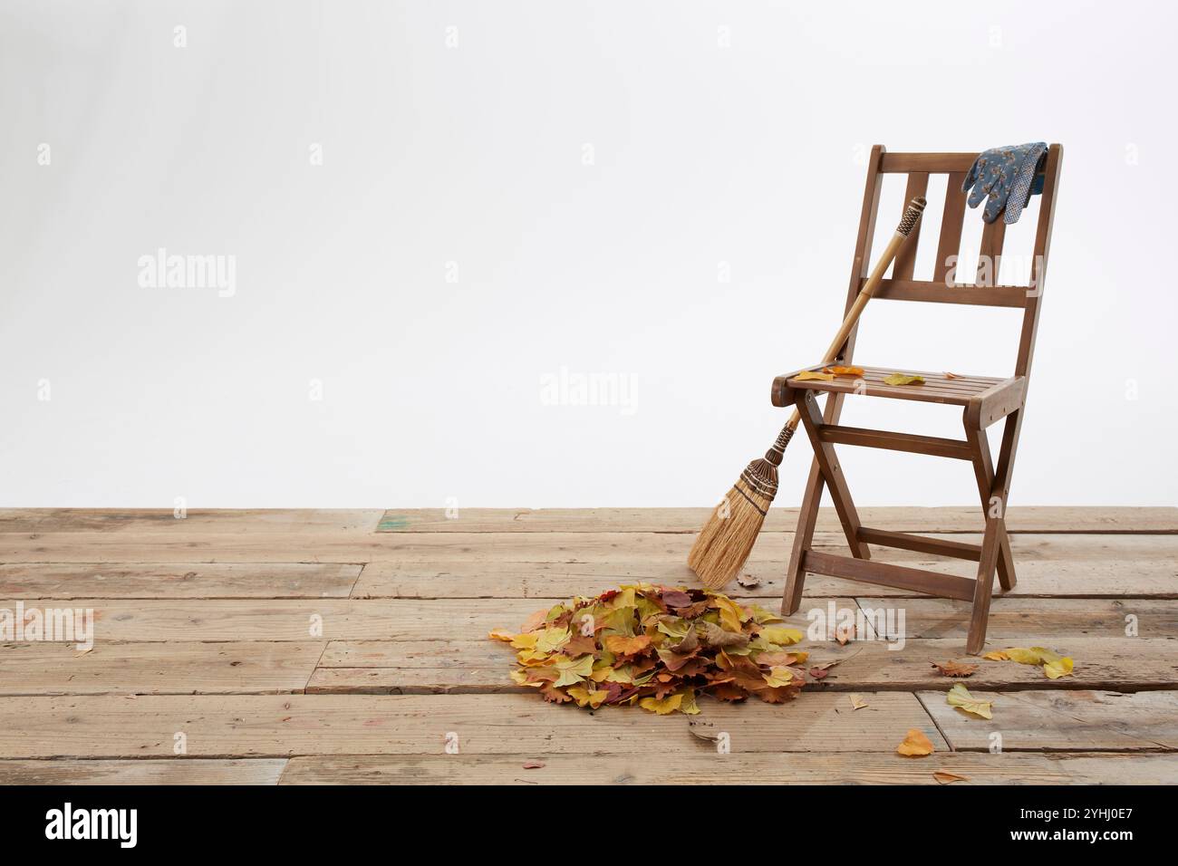 Chaise en bois sur le pont avec feuilles mortes et balai Banque D'Images