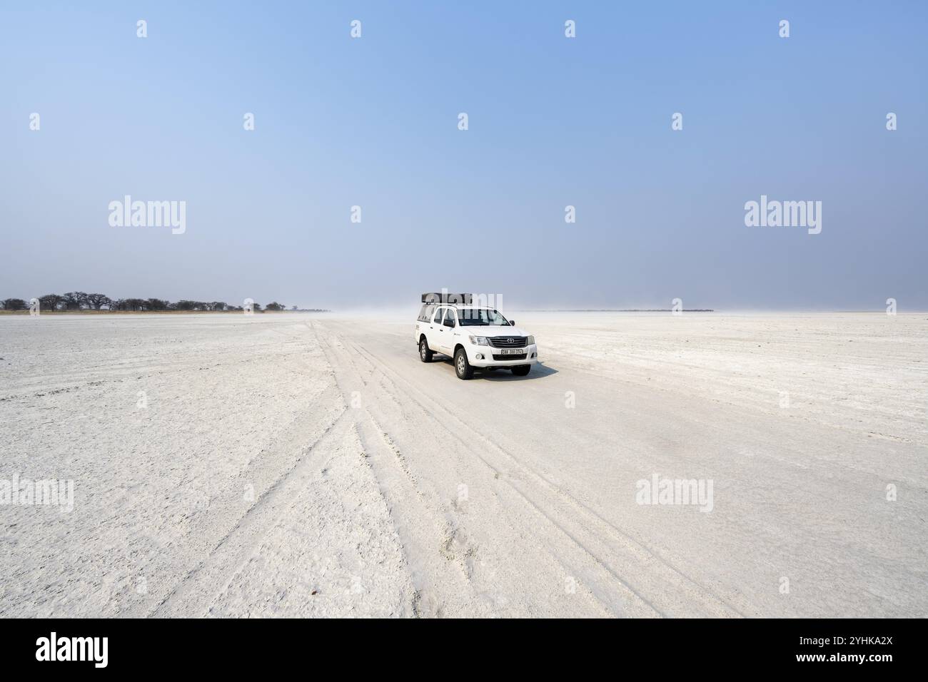 Toyota Hilux à quatre roues motrices avec tente de toit, conduite sur le bac à sel, voiture solitaire dans une grande plaine large, parc national de Nxai Pan, Botswana, Afrique Banque D'Images