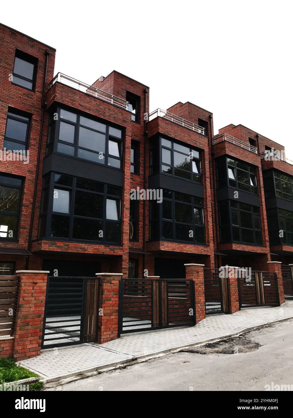 Cette image met en valeur une rangée de maisons de ville modernes en brique avec de grandes fenêtres et une architecture contemporaine. Parfait pour illustrer la vie urbaine, re Banque D'Images