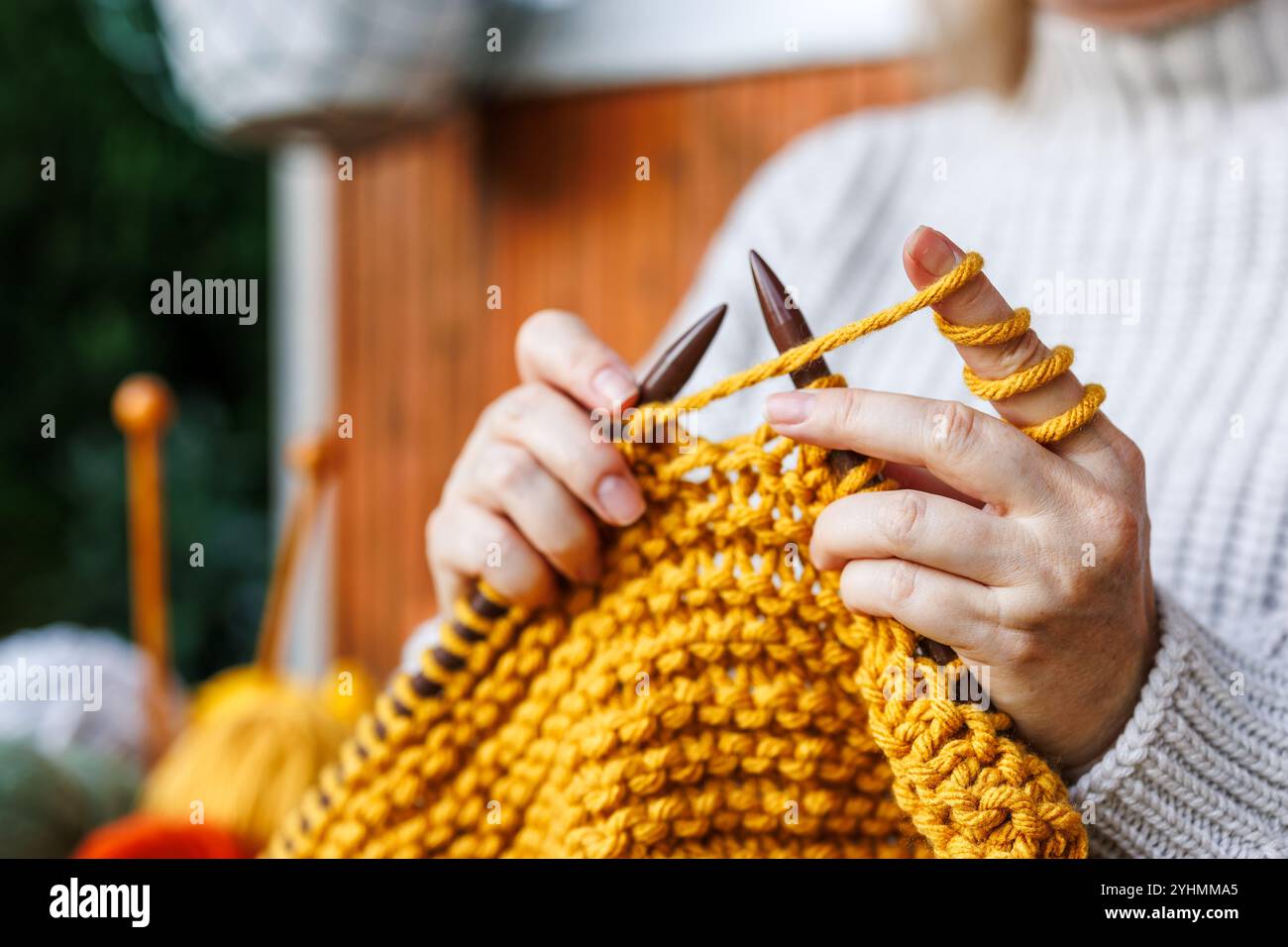 Tricoter avec de la laine. Femme en pull en laine tricote des vêtements chauds de fil jaune Banque D'Images