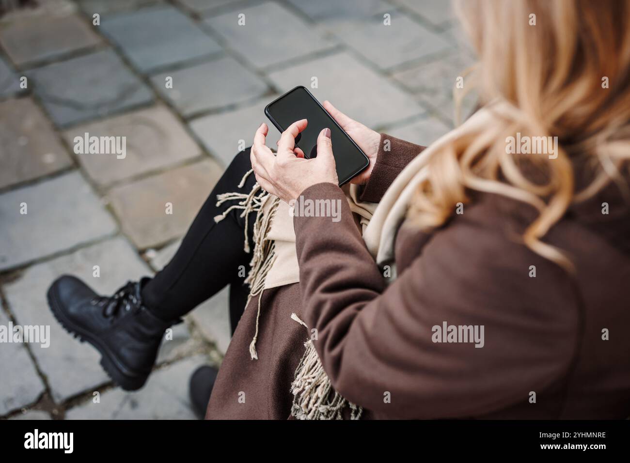 Femme assise sur le banc à la rue de la ville et à l'aide d'un smartphone. Connexion et messagerie texte sur téléphone mobile pendant les escapades en ville Banque D'Images