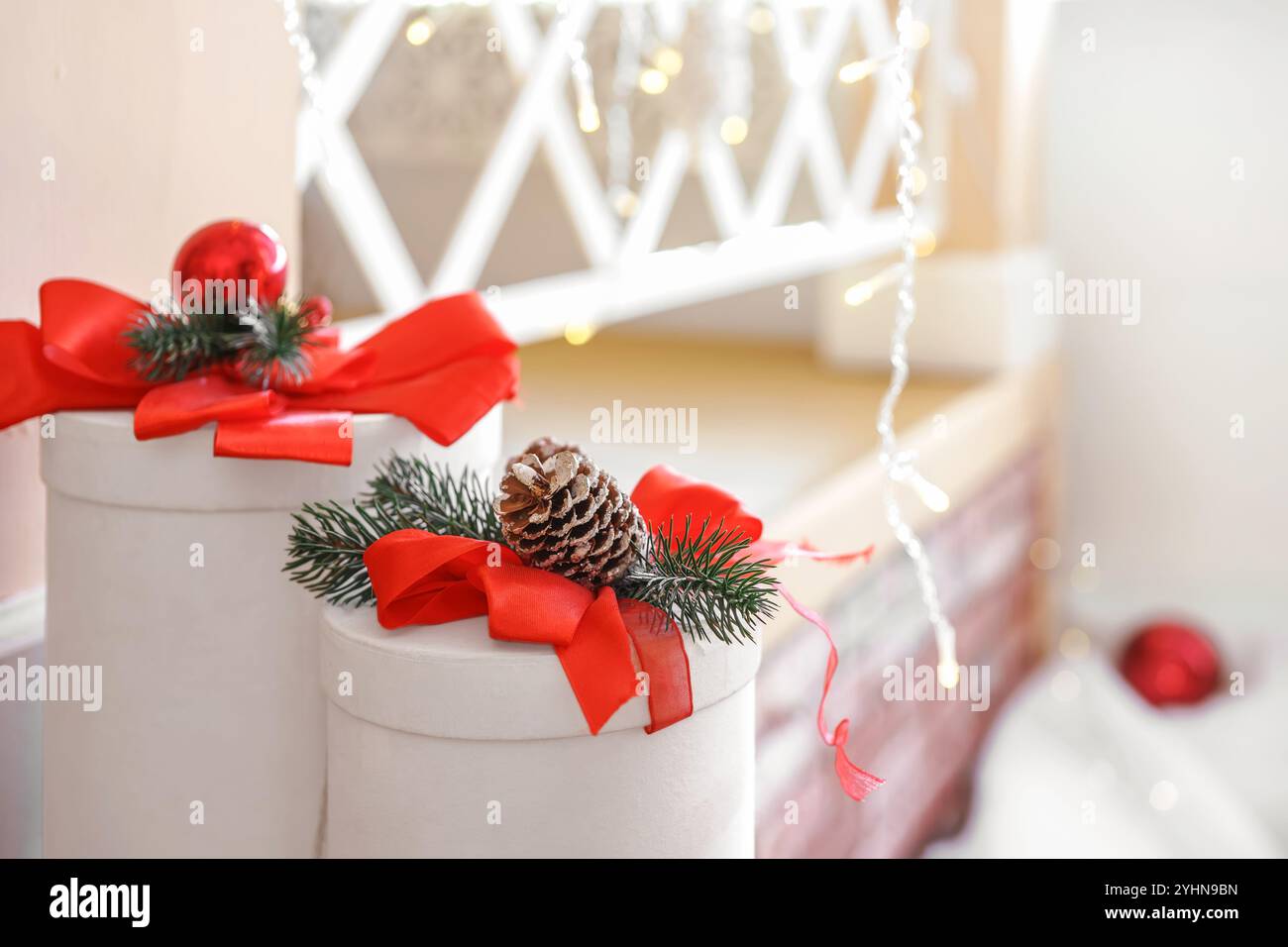 Deux coffrets cadeaux blancs ronds décorés avec des noeuds rouges, branche d'épinette et cône, créant une atmosphère joyeuse parfaite saison des vacances d'hiver. Noël et Banque D'Images