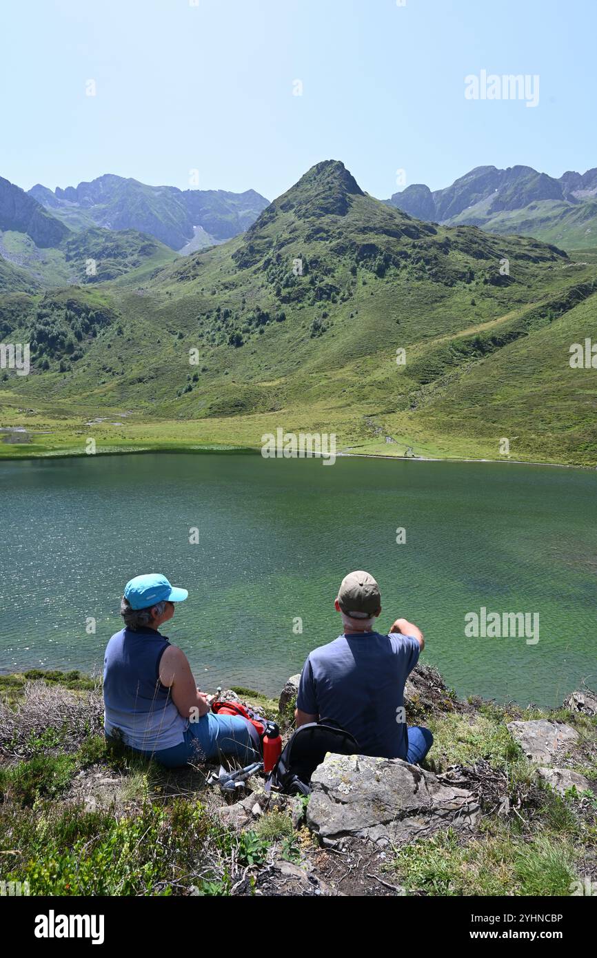 Couple de marcheurs profiter pique-nique & vue sur le lac Isaby ou le lac d'Isaby, un lac glaciaire, dans les Hautes-Pyrénées ou Pyrénées montagnes France Banque D'Images