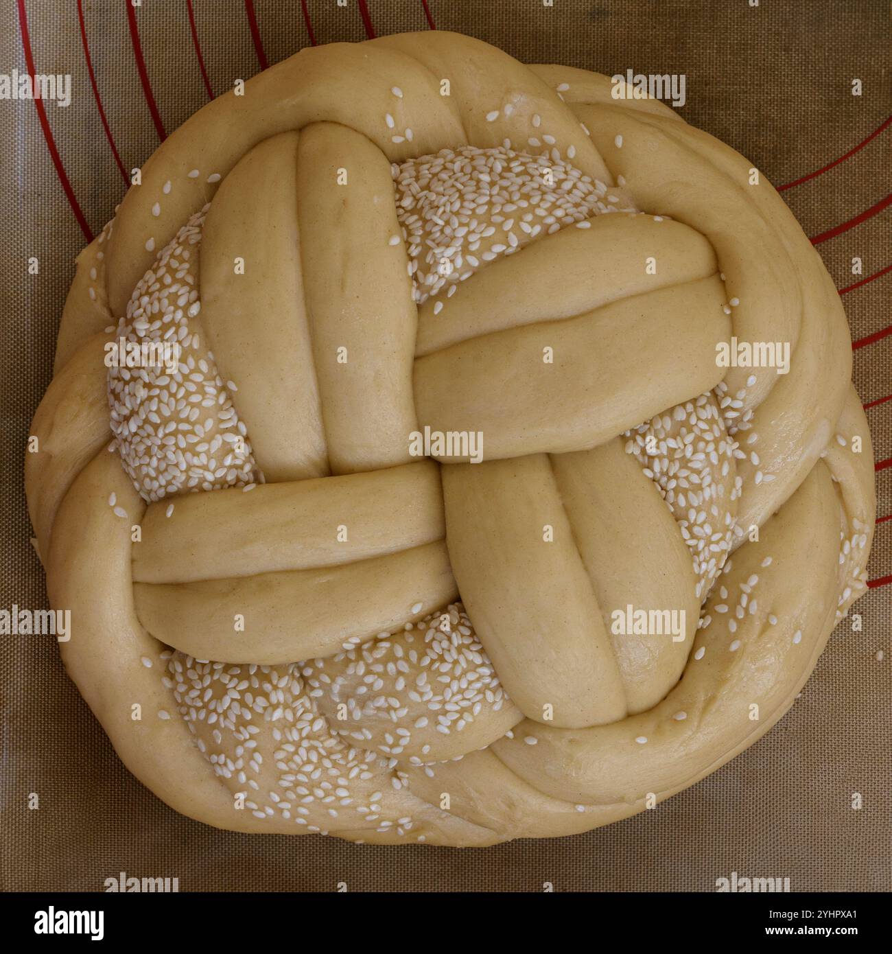 Pain de challah juif non cuit, rond, tressé, garni de graines de sésame. Banque D'Images