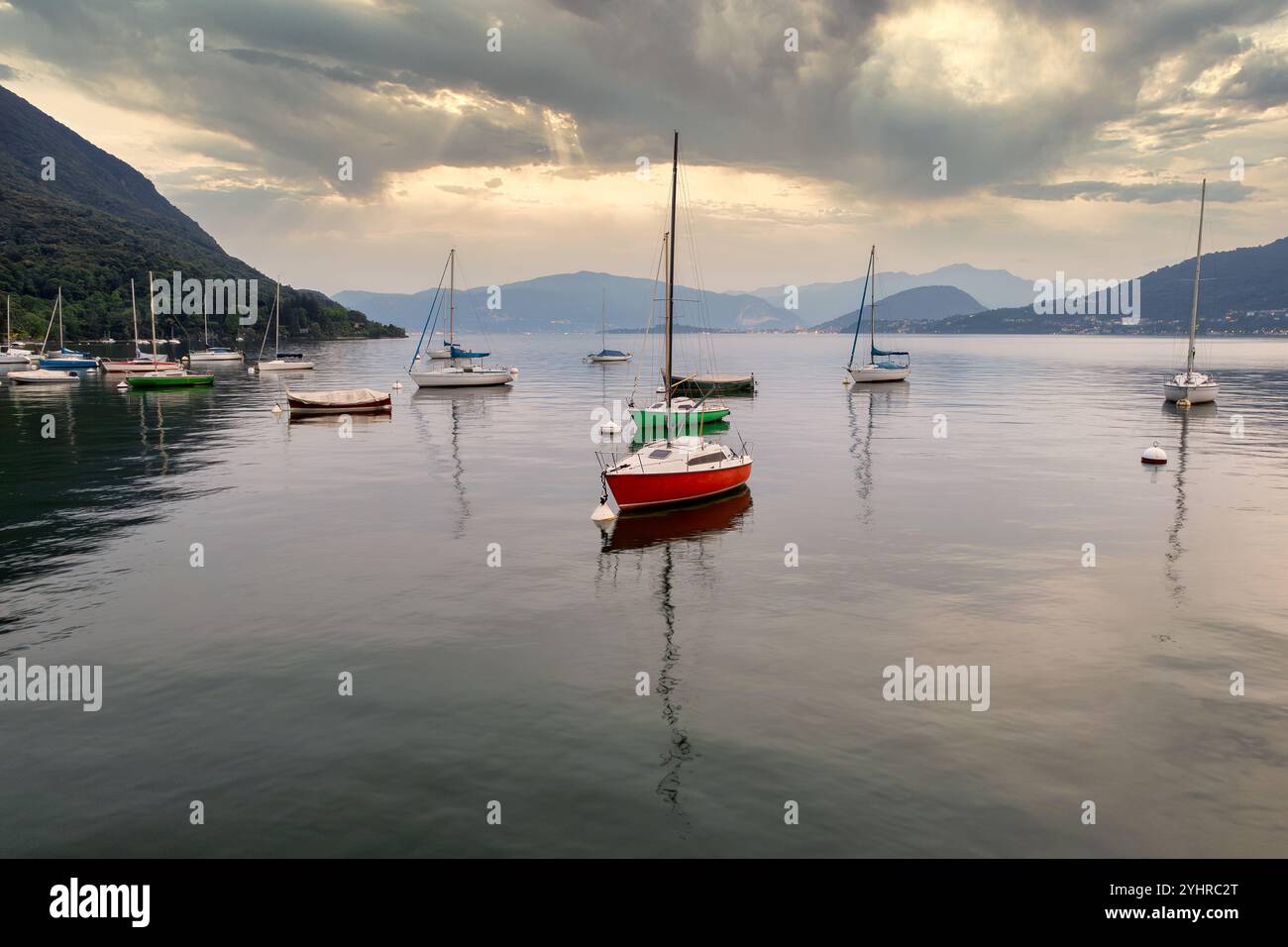 Des voiliers sereins amarrés sur les eaux calmes du lac de Côme, en Italie - Une vue panoramique paisible avec collines brumeuses et réflexions tranquilles Banque D'Images