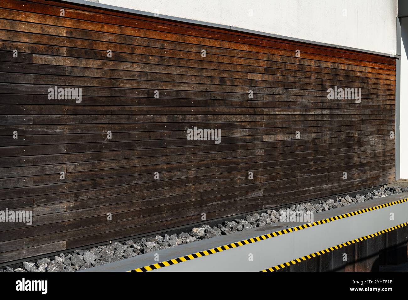 Un mur en bois altéré affiche une texture rustique à côté d'un chemin de pierre. La scène est éclairée par la lumière du jour, mettant en évidence le contraste entre Banque D'Images