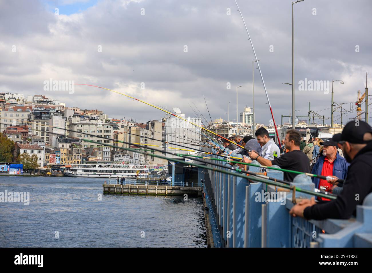 25/10/2024. Istanbul, Turquie. Pêcheurs sur le pont de Galata, qui a été construit par la société de construction turque STFA à quelques mètres du pont précédent, entre Karaköy et Eminönü, et achevé en décembre 1994. Il s'agit d'un pont basculant de 490 m (1 610 ft) de long avec une portée principale de 80 m (260 ft). Le pont du pont est large de 42 m (138 pi) et comporte deux voies de circulation et une passerelle dans chaque direction. Les voies de tramway qui descendent au milieu permettent au tramway T1 de circuler de Bağcılar, dans la banlieue ouest, à Kabataş. En 2003, une série de restaurants ont été ajoutés aux unders Banque D'Images