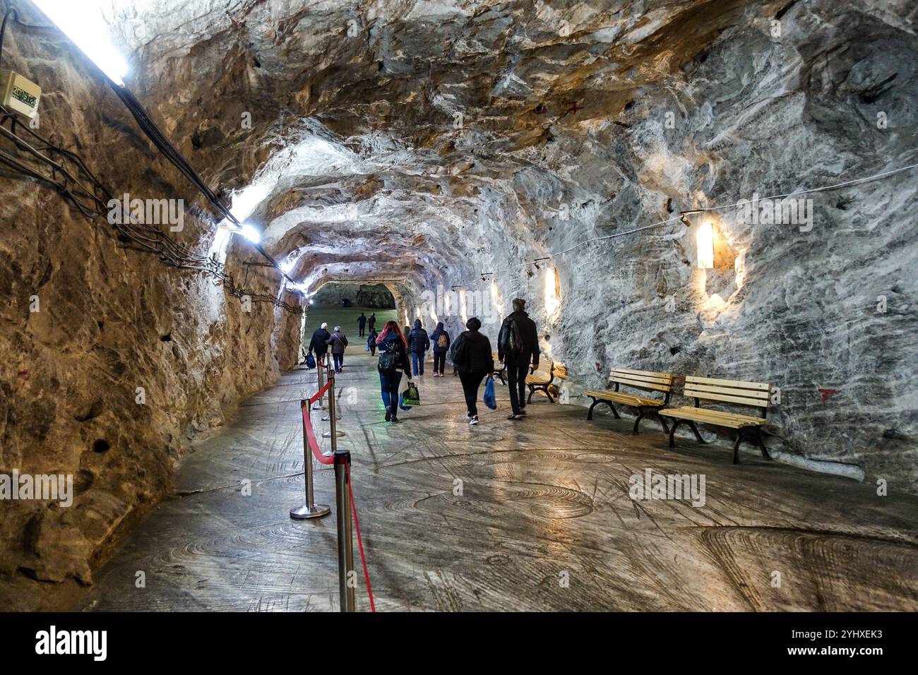 Touristes marchant dans la chambre souterraine massive de la mine de sel de Slanic, Roumanie, avec des murs illuminés Banque D'Images