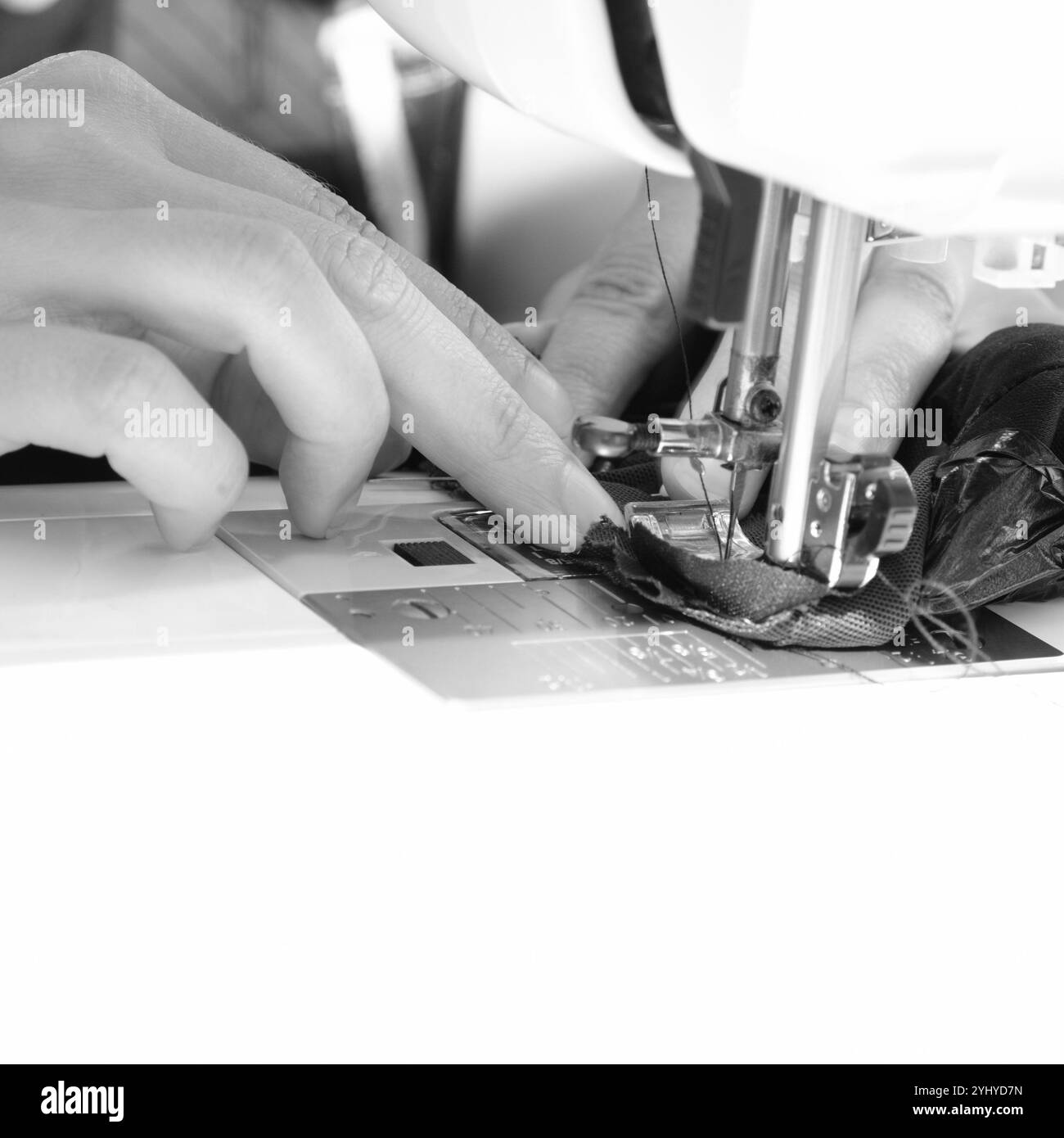 Jeune femme couturière coud des vêtements sur la machine à coudre gros plan. Banque D'Images